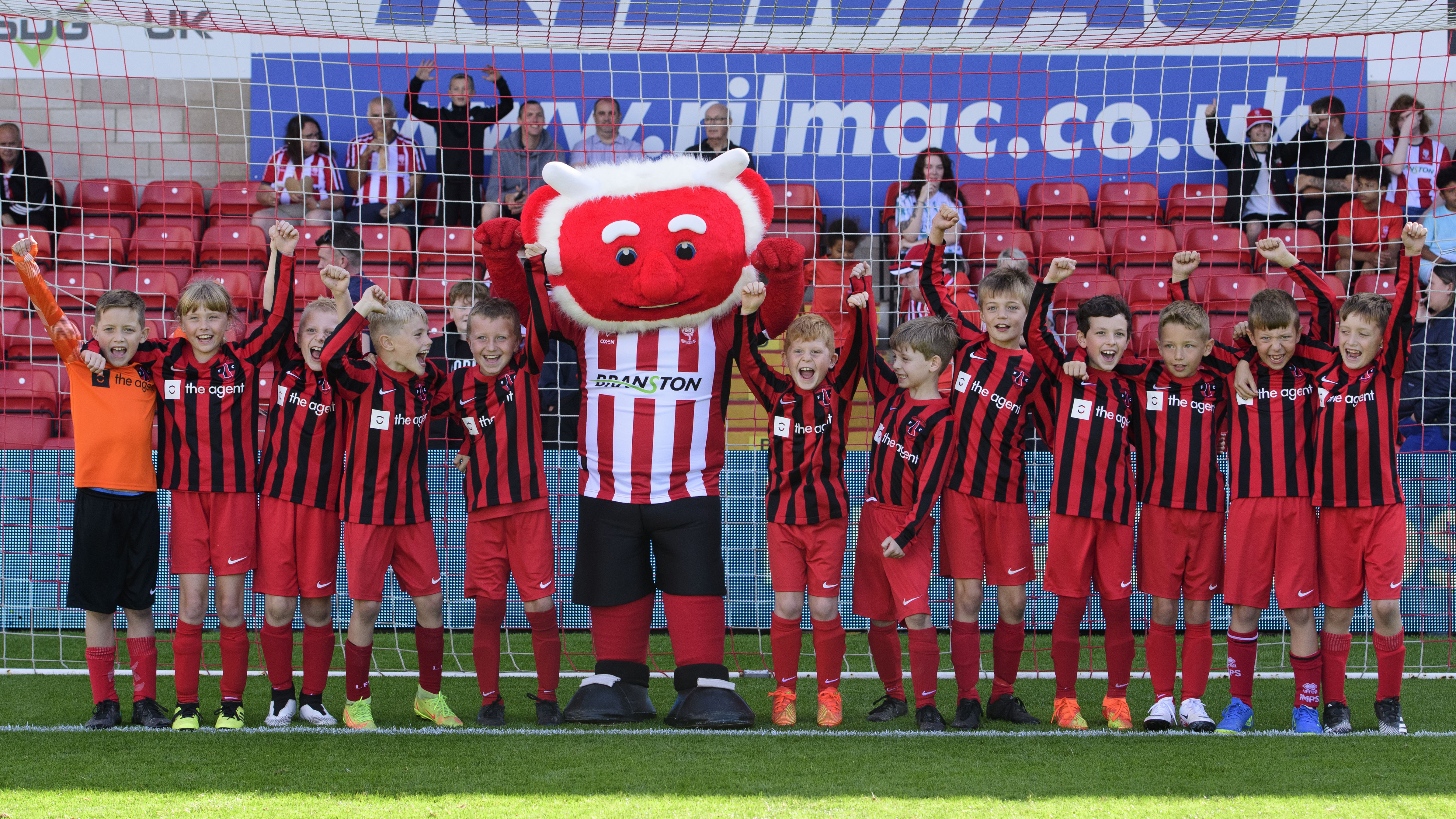 Poacher the Imp poses with a group of children who took part in a penalty shootout against him.
