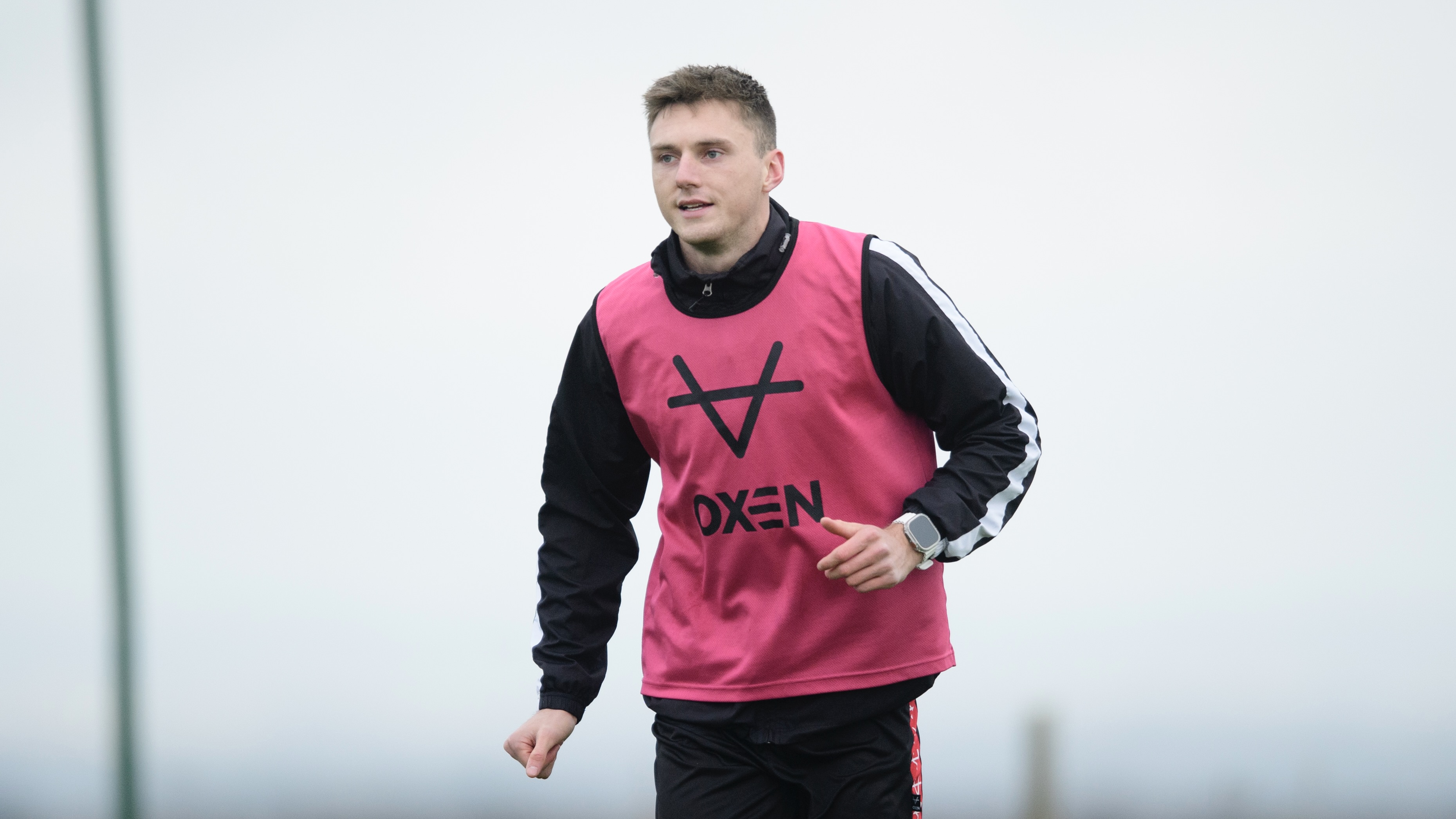 Hayden Cann during training. He is wearing a pink bib over a black jacket.
