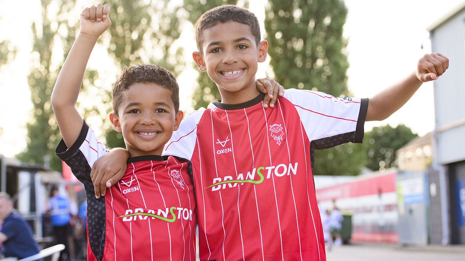 A pair of young City fans outside the stadium wearing the 24/25 home shirt