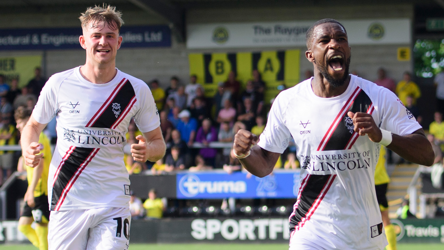 Tendai Darikwa, right, celebrates with a large smile after scoring against Burton Albion. Team-mate JJ McKiernan is running after him. Both players are wearing predominantly-white kits.