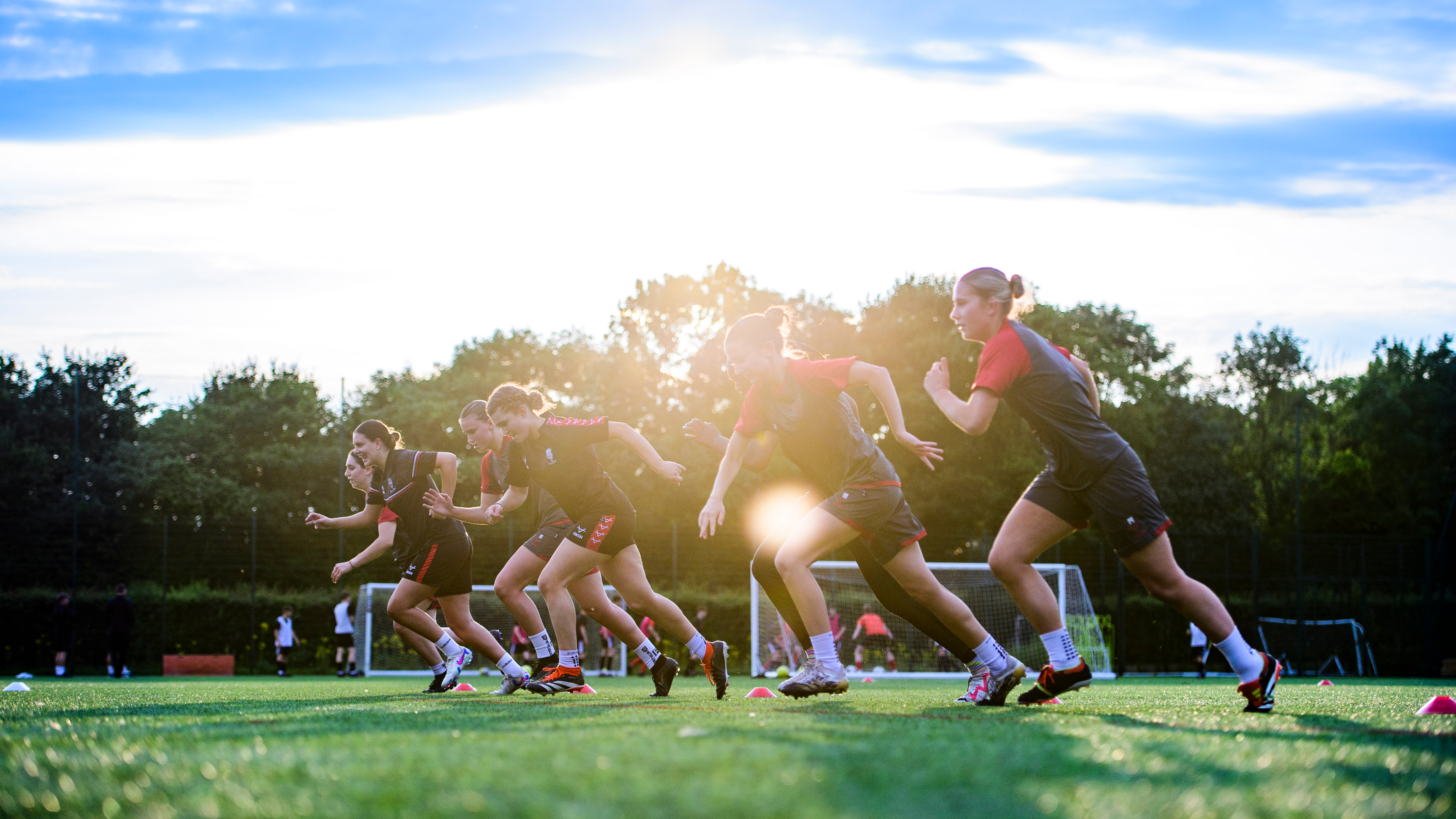 Several Lincoln City Women carry out a running drill on sunny day.