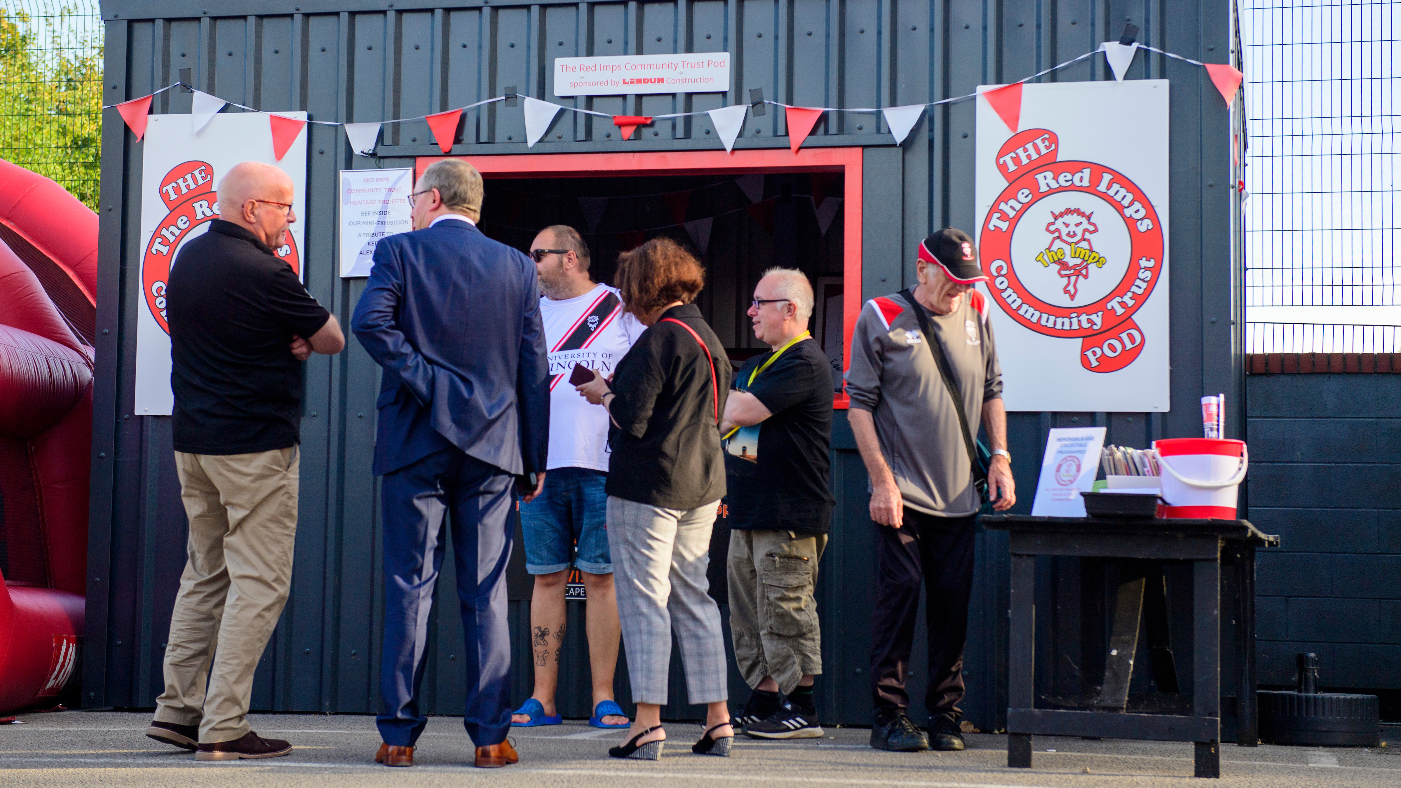 Lincoln City supporters stand in front of the Red Imps Community Trust pod