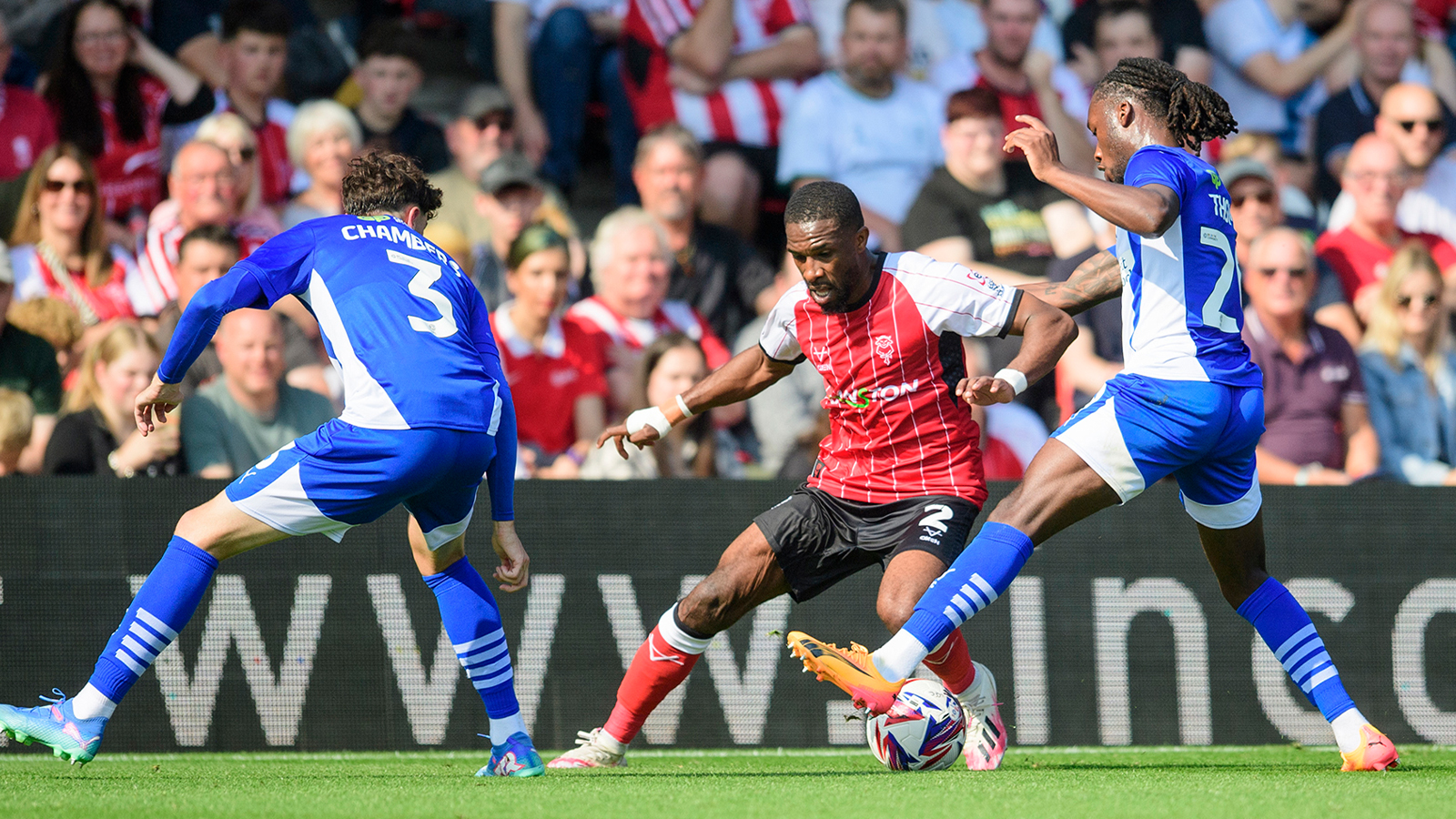 Tendayi Darikwa tries to take the ball past two Wigan players.