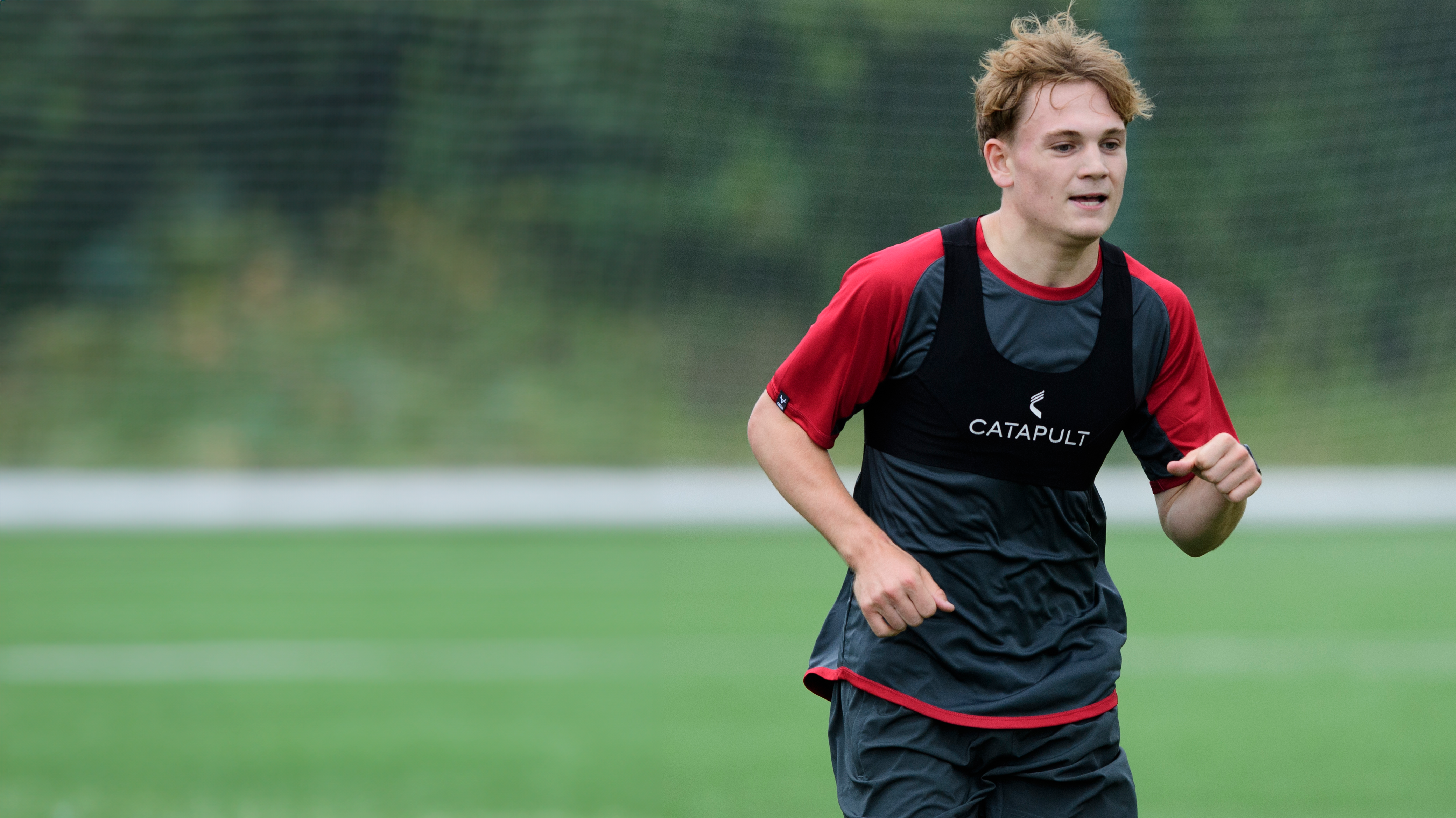 Carter Ford running on a training pitch. H is wearing a black and red training top.