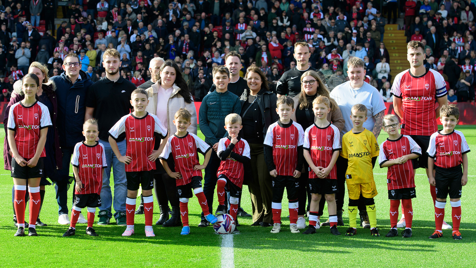 Mascots line up on the pitch before a Lincoln City home game.