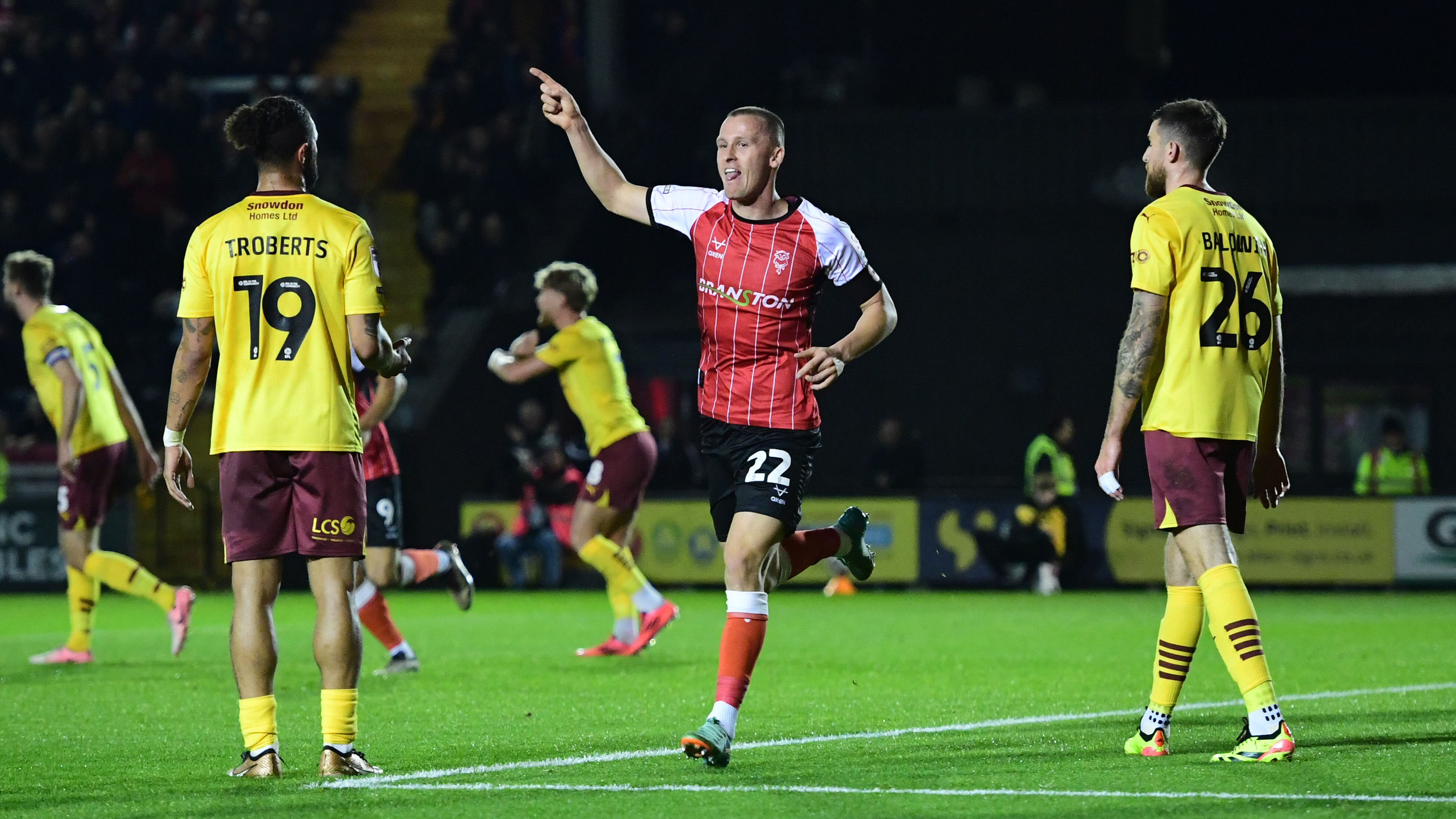 Tom Hamer celebrates scoring his goal. He is holding his right hand up and pointing as he runs away in celebration.