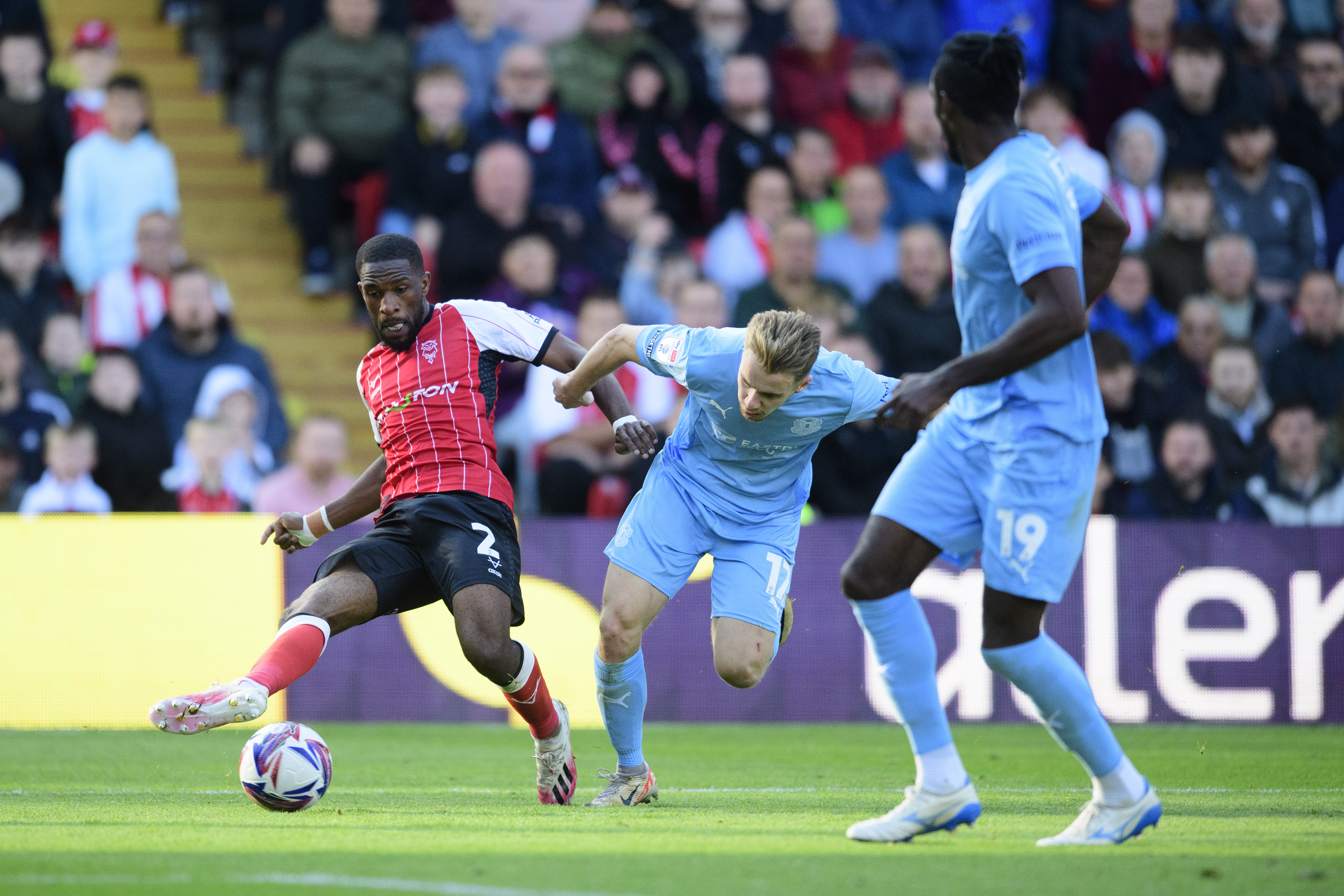 Tendayi Darikwa passes the ball with his right foot. He is challenged by a Leyton Orient player.