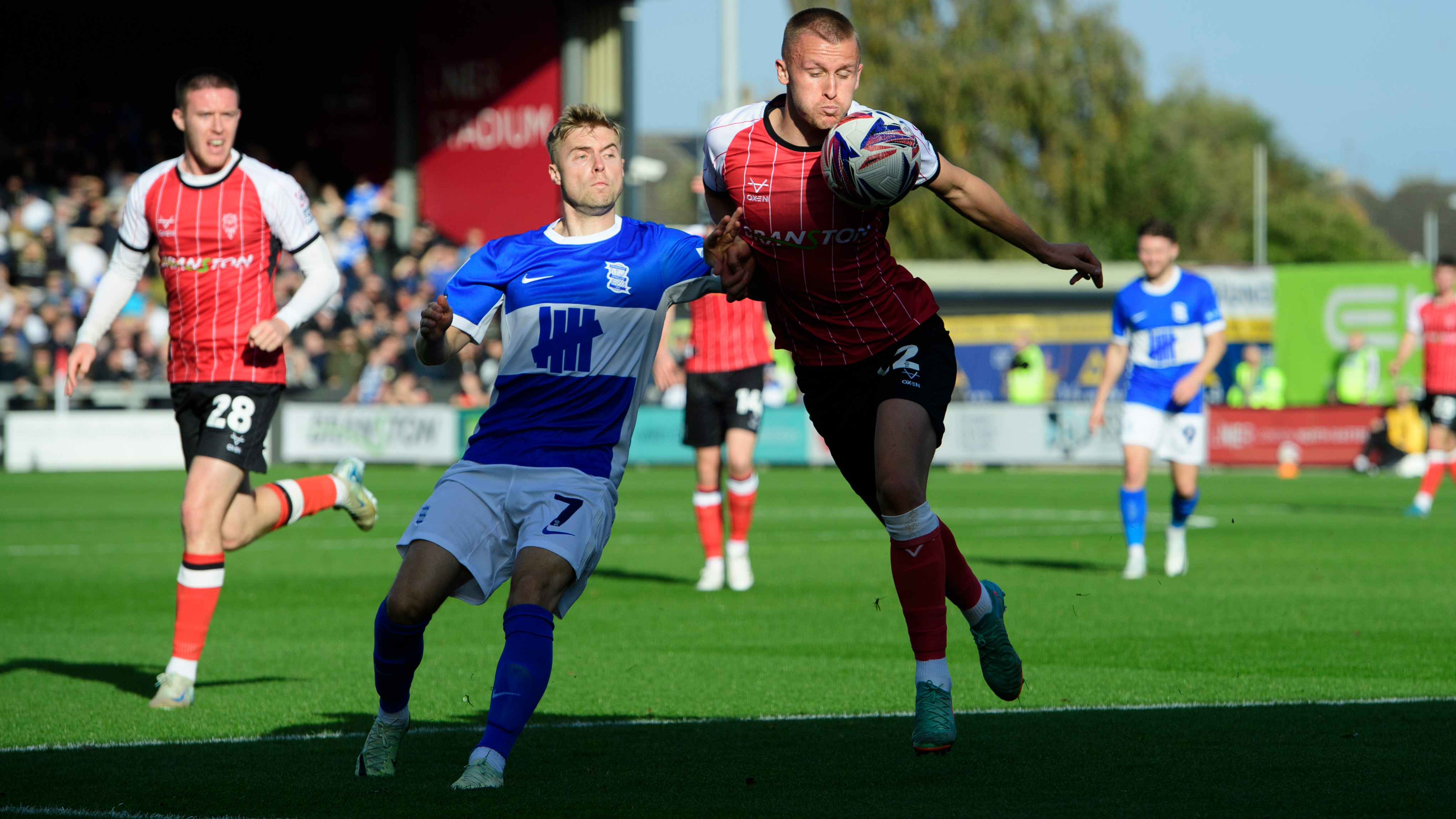 Lincoln City player Tom Hamer challenges for the ball with a Birmingham City player.