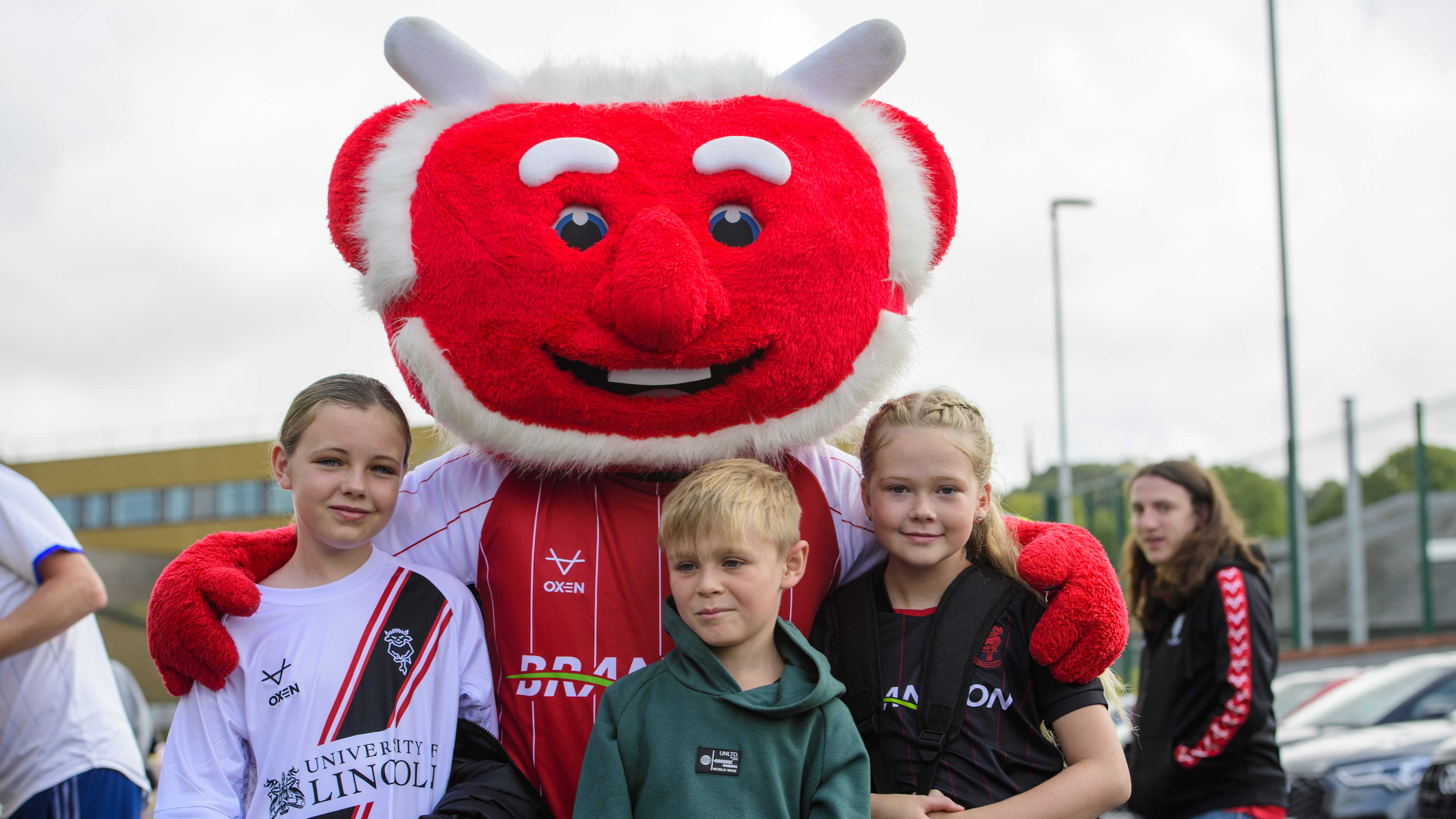 Poacher the Imp poses with his arms around a group of young childten