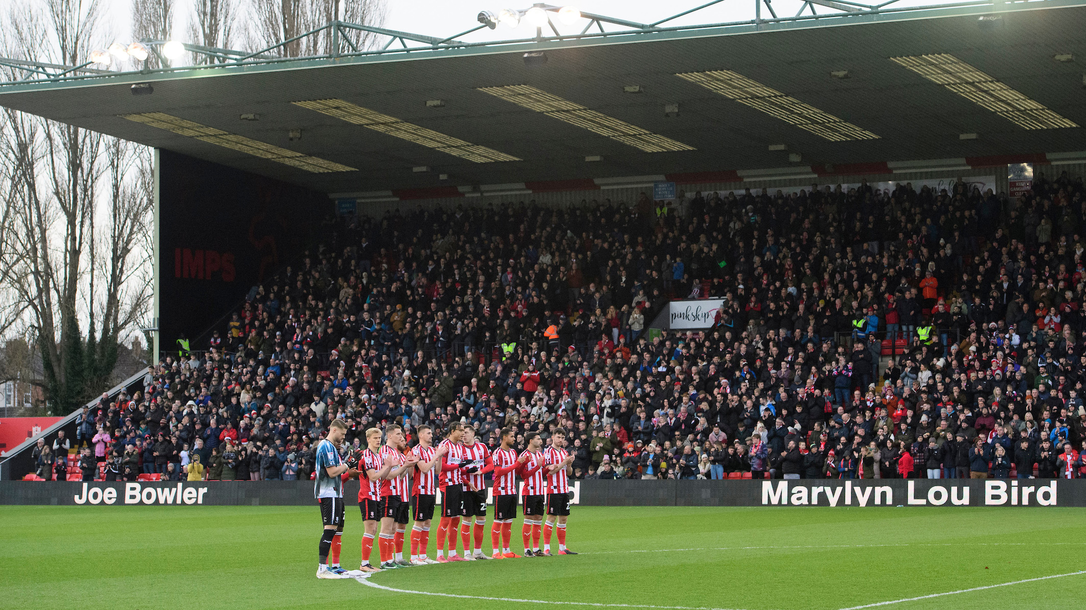 Lincoln City footballers line up for a minute's applause.