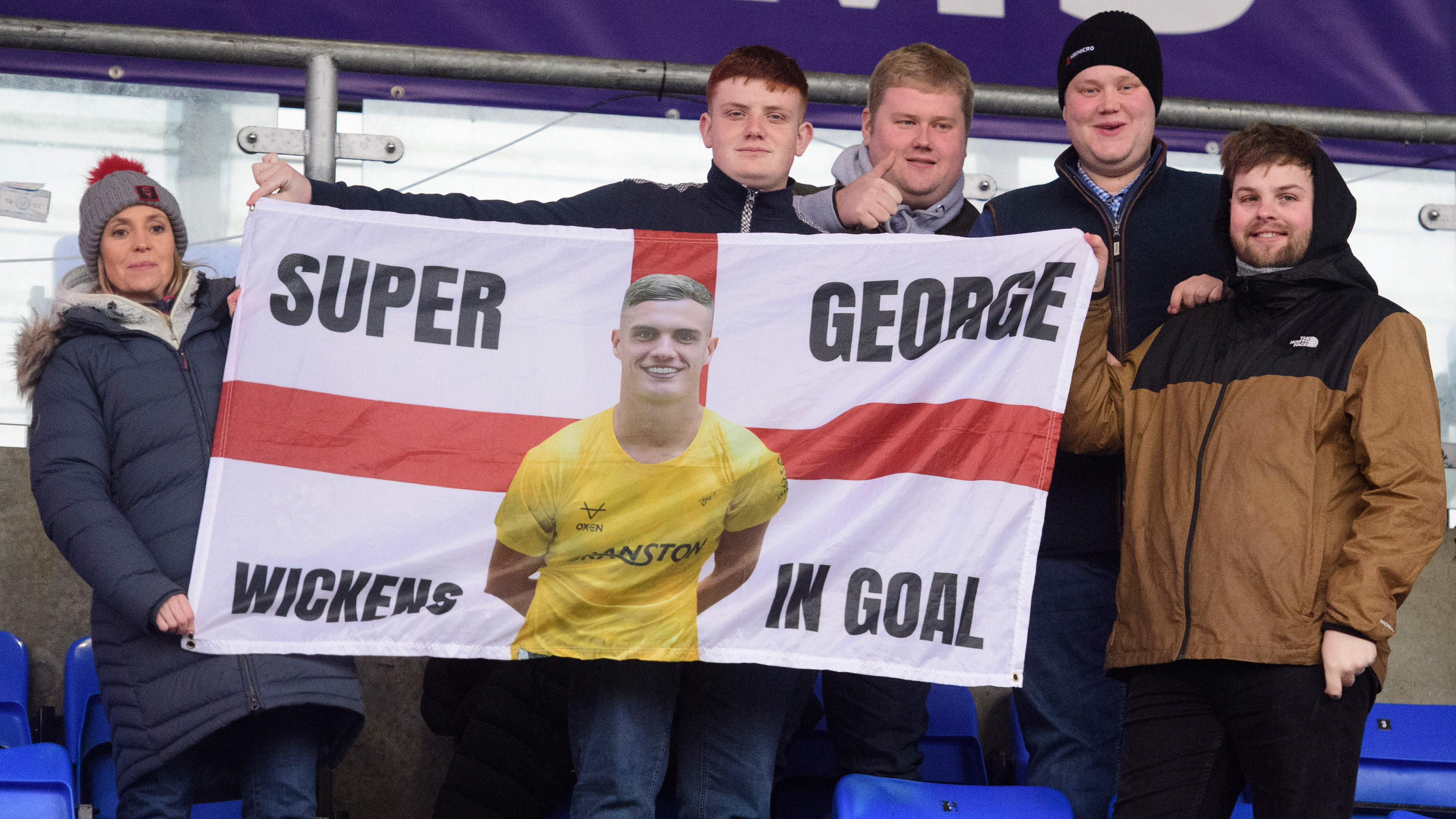 Five people hold up a flag which reads "Super George Wickens in goal".