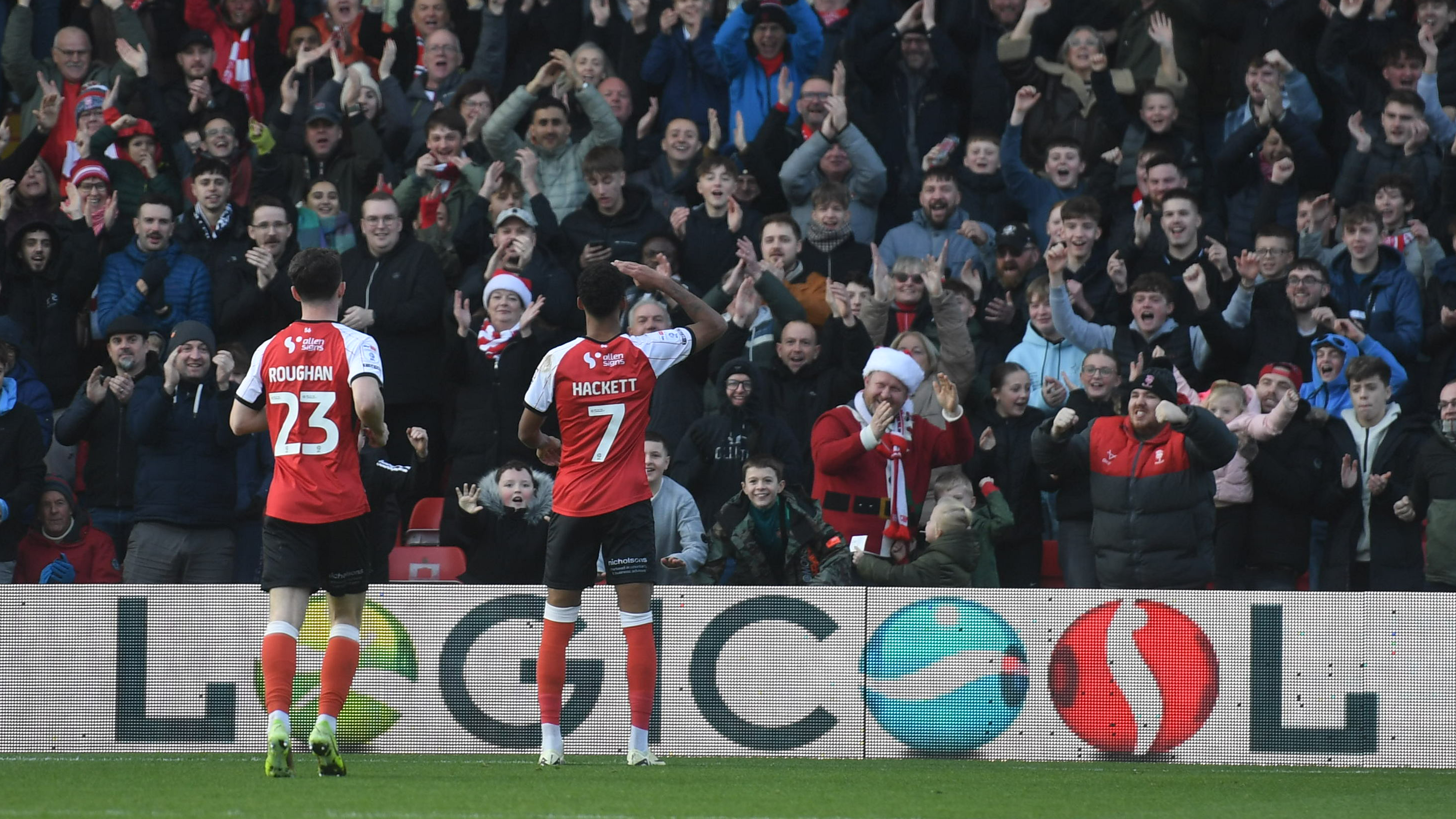 Sean Roughan and Reeco Hackett are pictured from behind celebrating a goal with fans. 