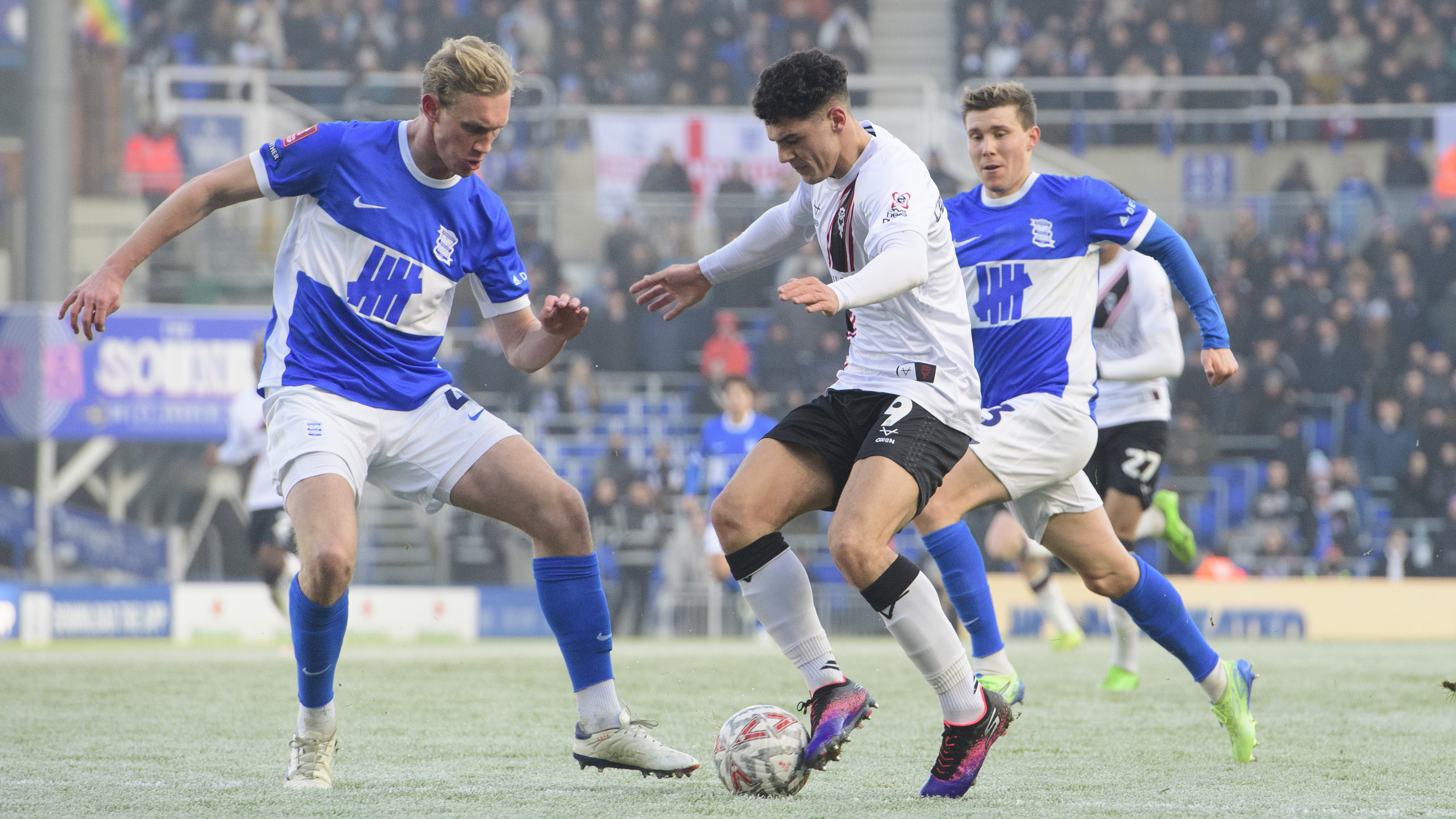 Bailey Cadamarteri,in a white shirt, tries to get away from two Birmingham City players