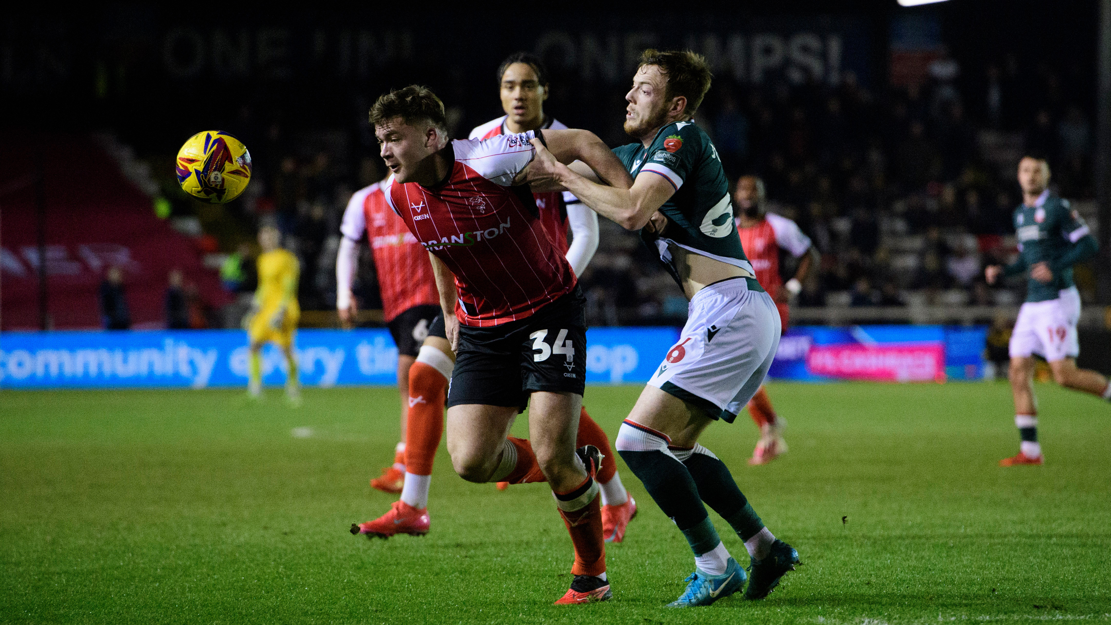 Freddie Draper, wearing a red shirt, tries to get away from a Bolton player in a green shirt.