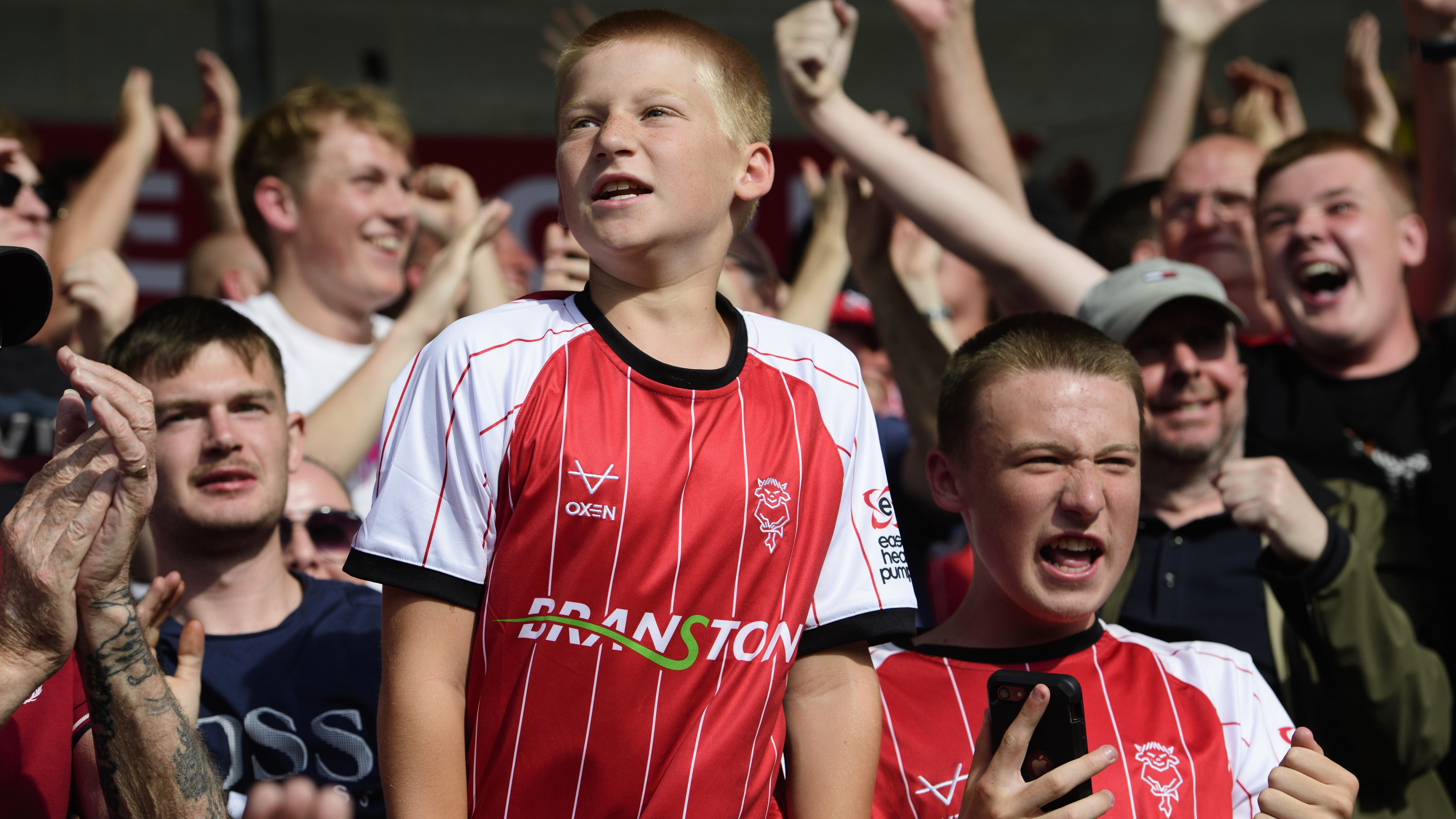 A Lincoln City fan in a red shirt celebrates a goal