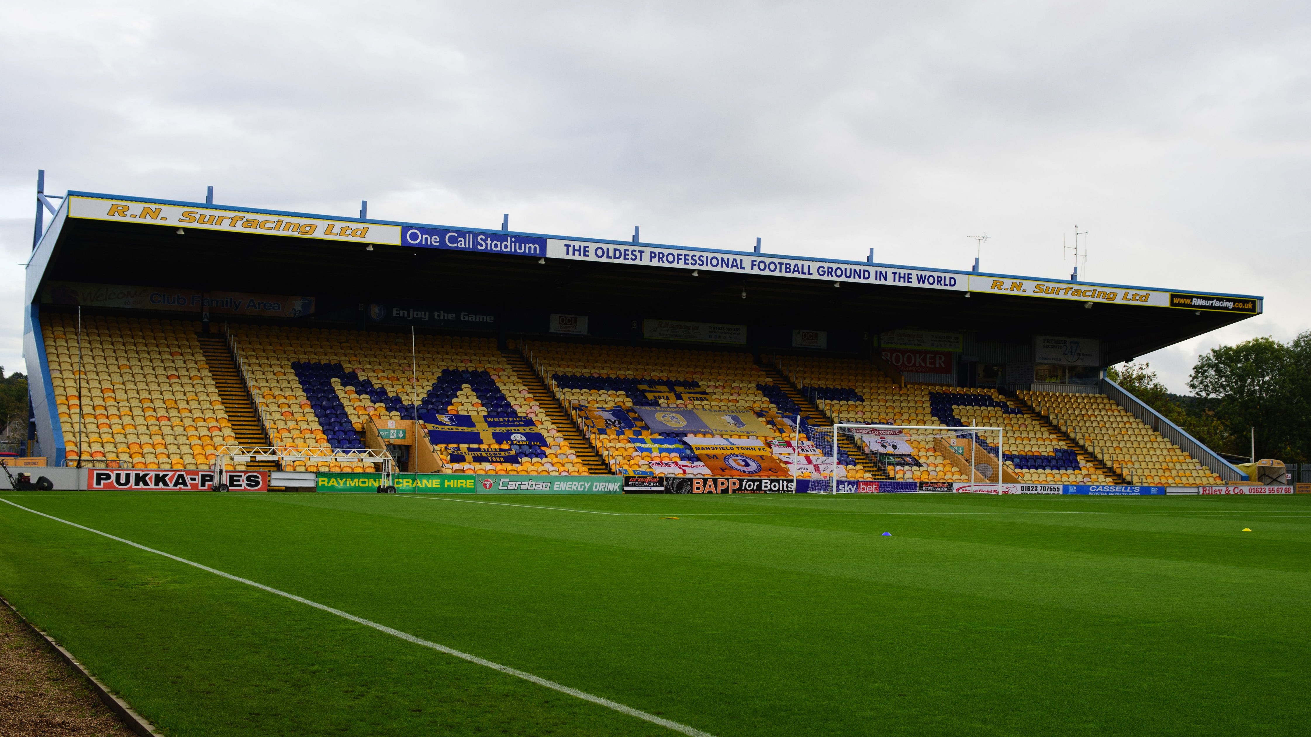 A general view of a stand at the One Call Stadium in Mansfield. The stand is yellow with MTFC written in blue with seats.