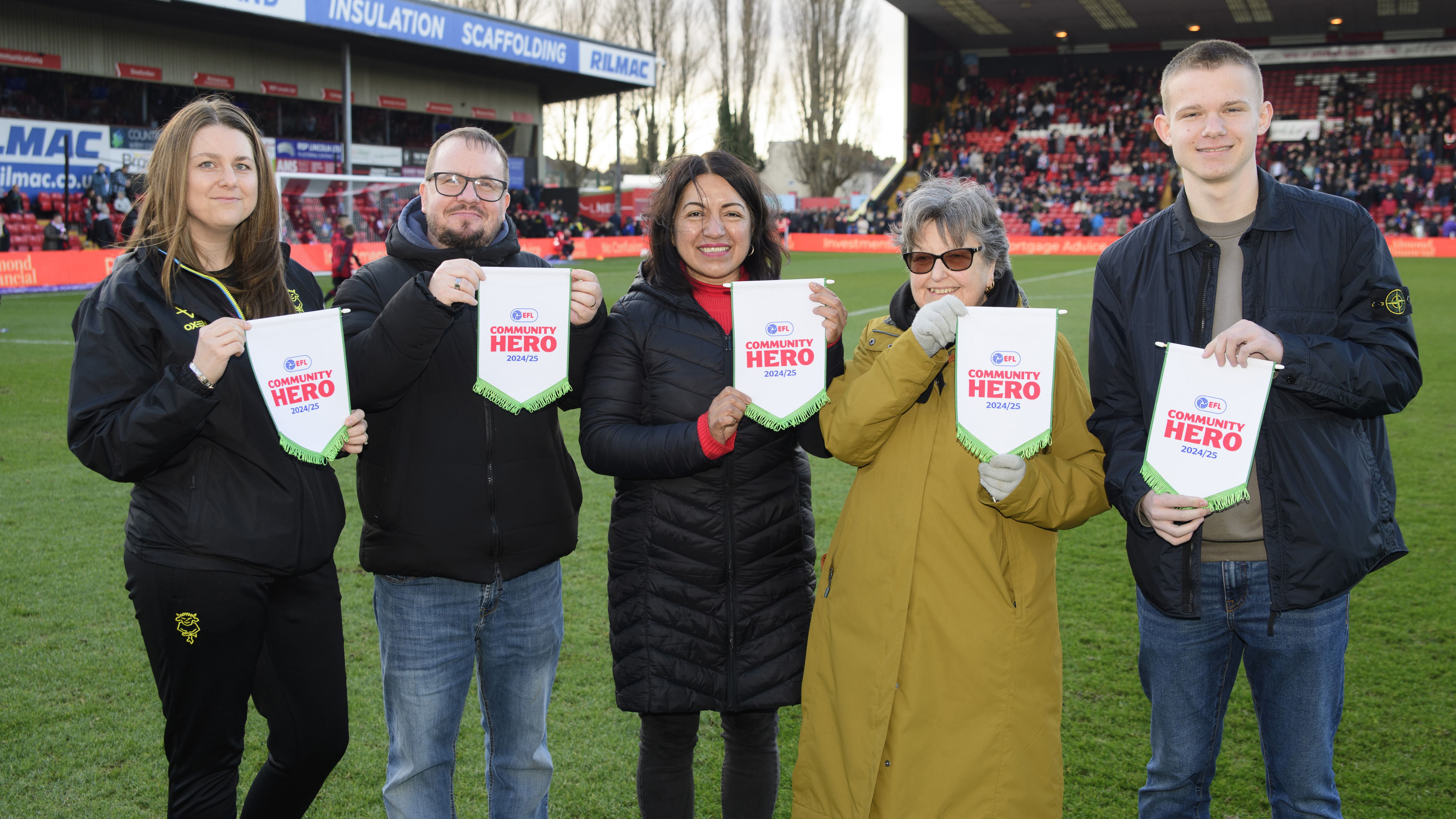 Five people stand in a line holding up pennants which read "EFL Community Hero"