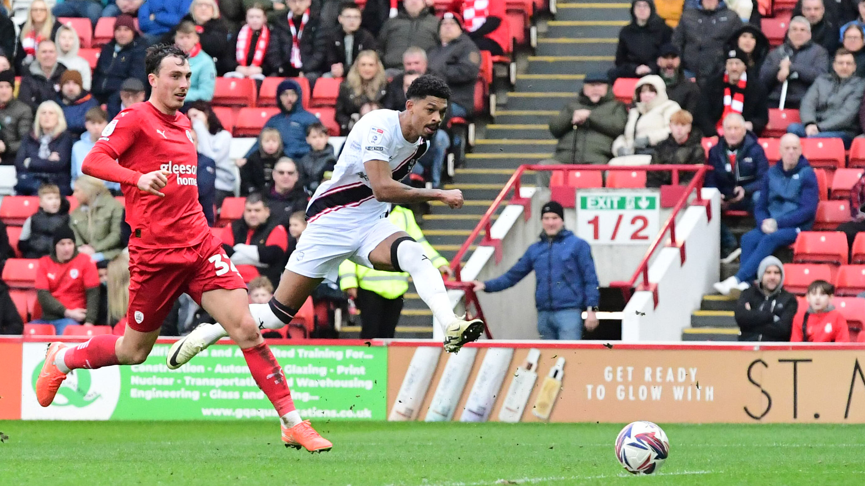 Reeco Hackett scores with a left-footed shot. The ball has left his foot and is going towards goal.