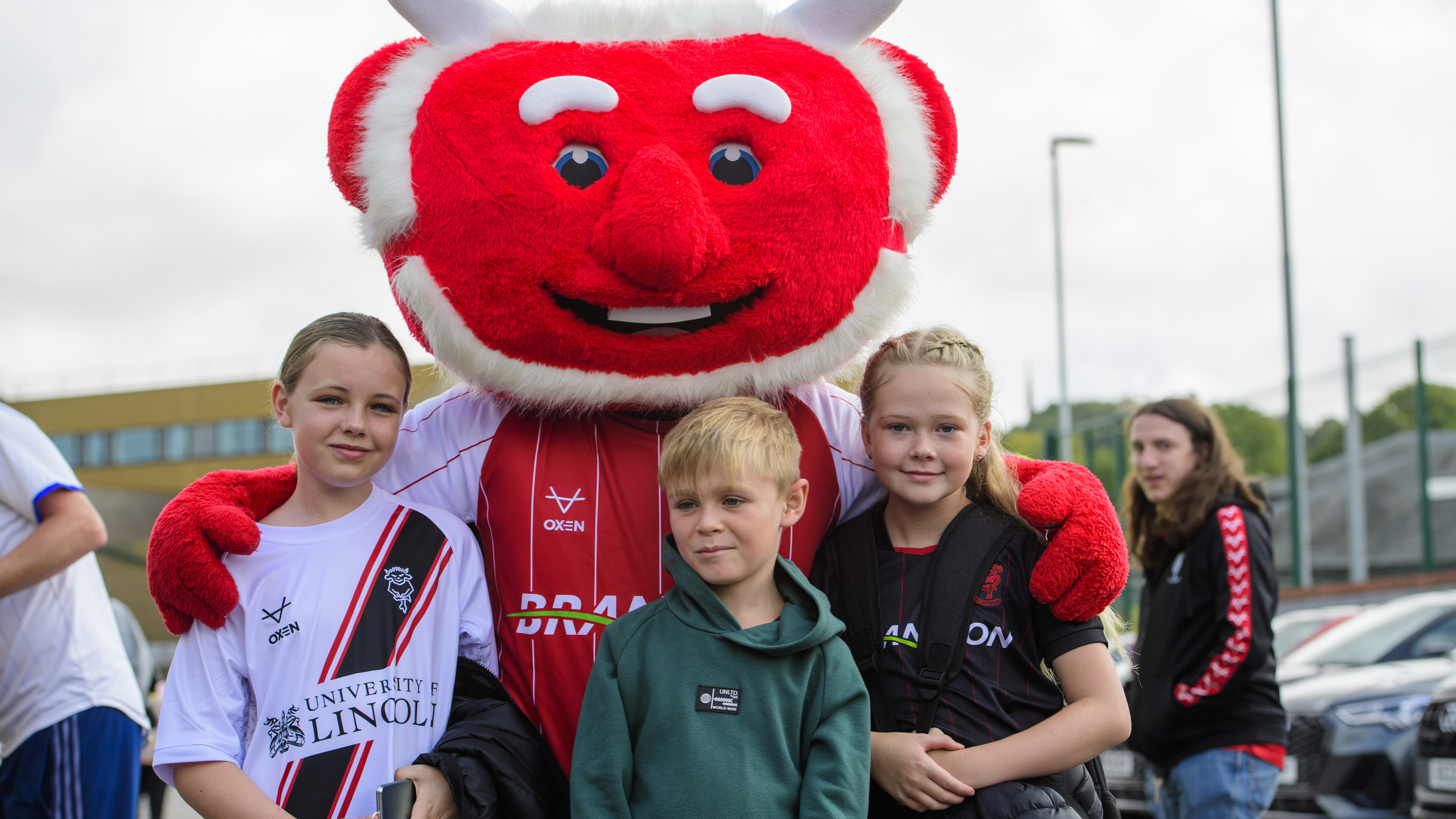 Three young Lincoln City fans pose with Poacher the Imp