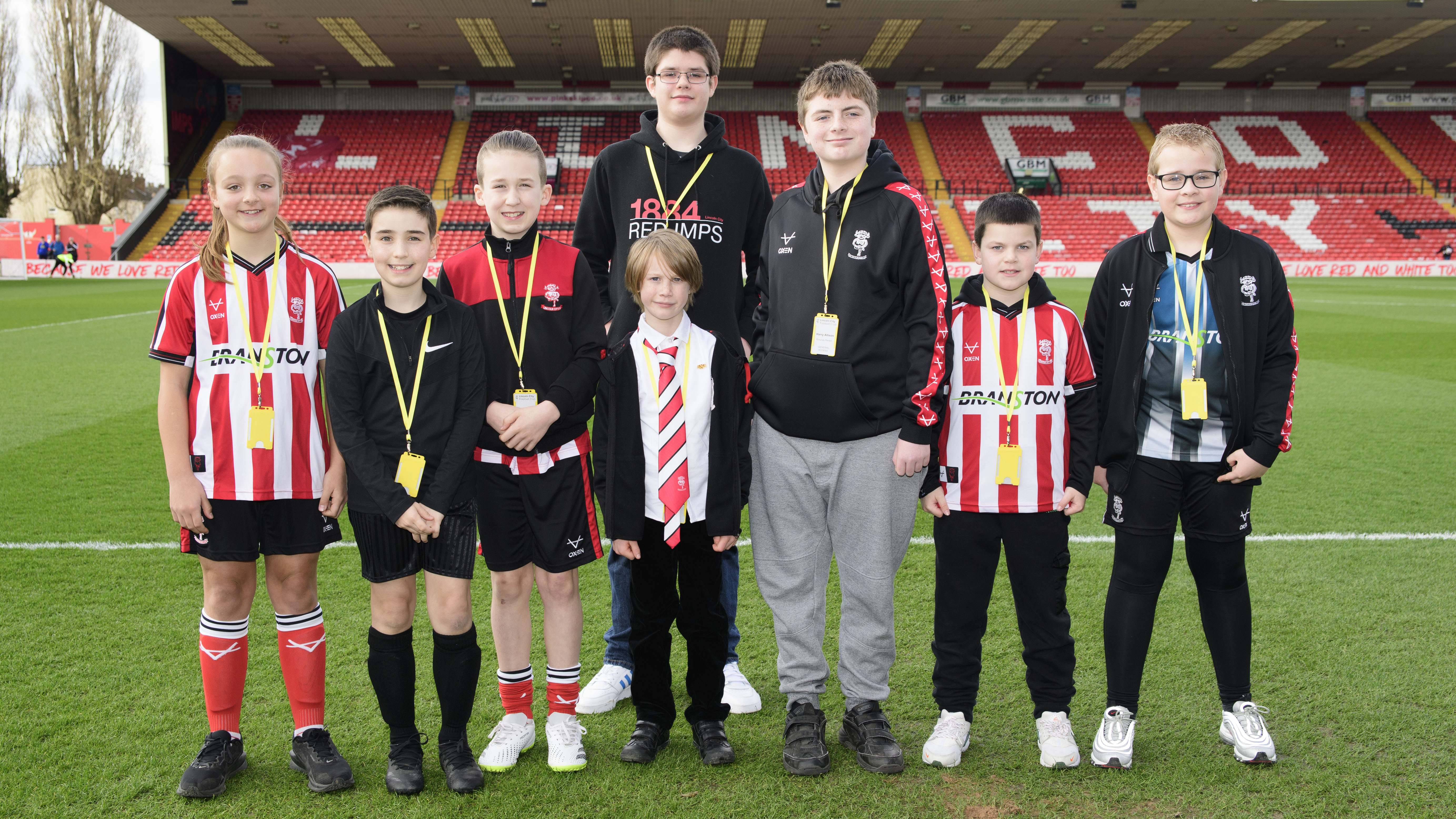 A group of children pose by a football pitch.