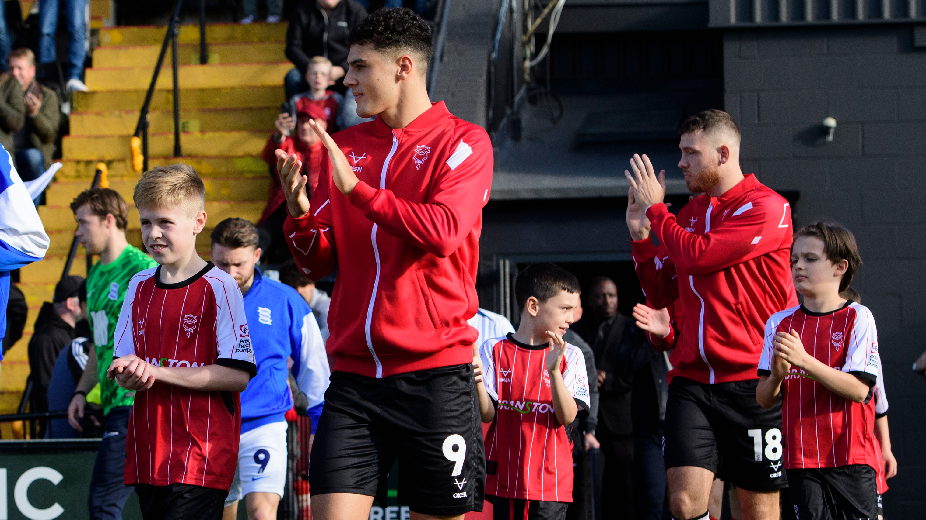 Children and players walk out ahead of a Lincoln City football match