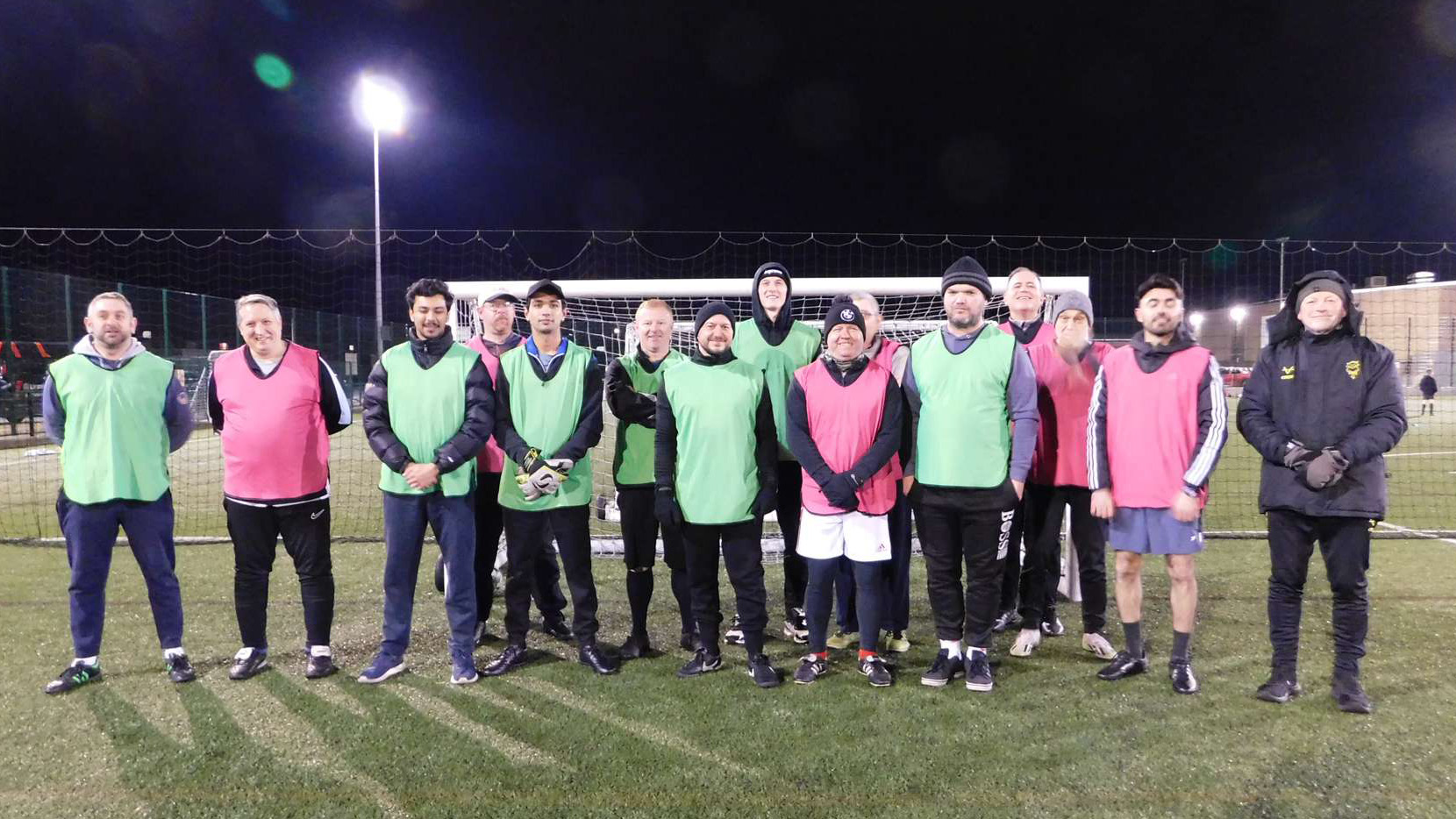 A group of people stand on a football pitch.