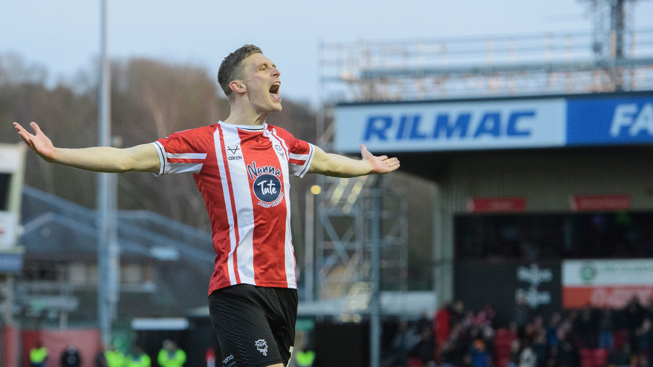 Ethan Hamilton celebrates a goal. He is looking from left to right and holding out his arms in celebration.