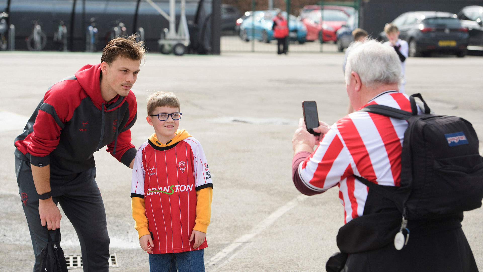 Erik Ring of Lincoln City poses for a photograph with a fan poses for a photograph with a fan outside the LNER Stadium.