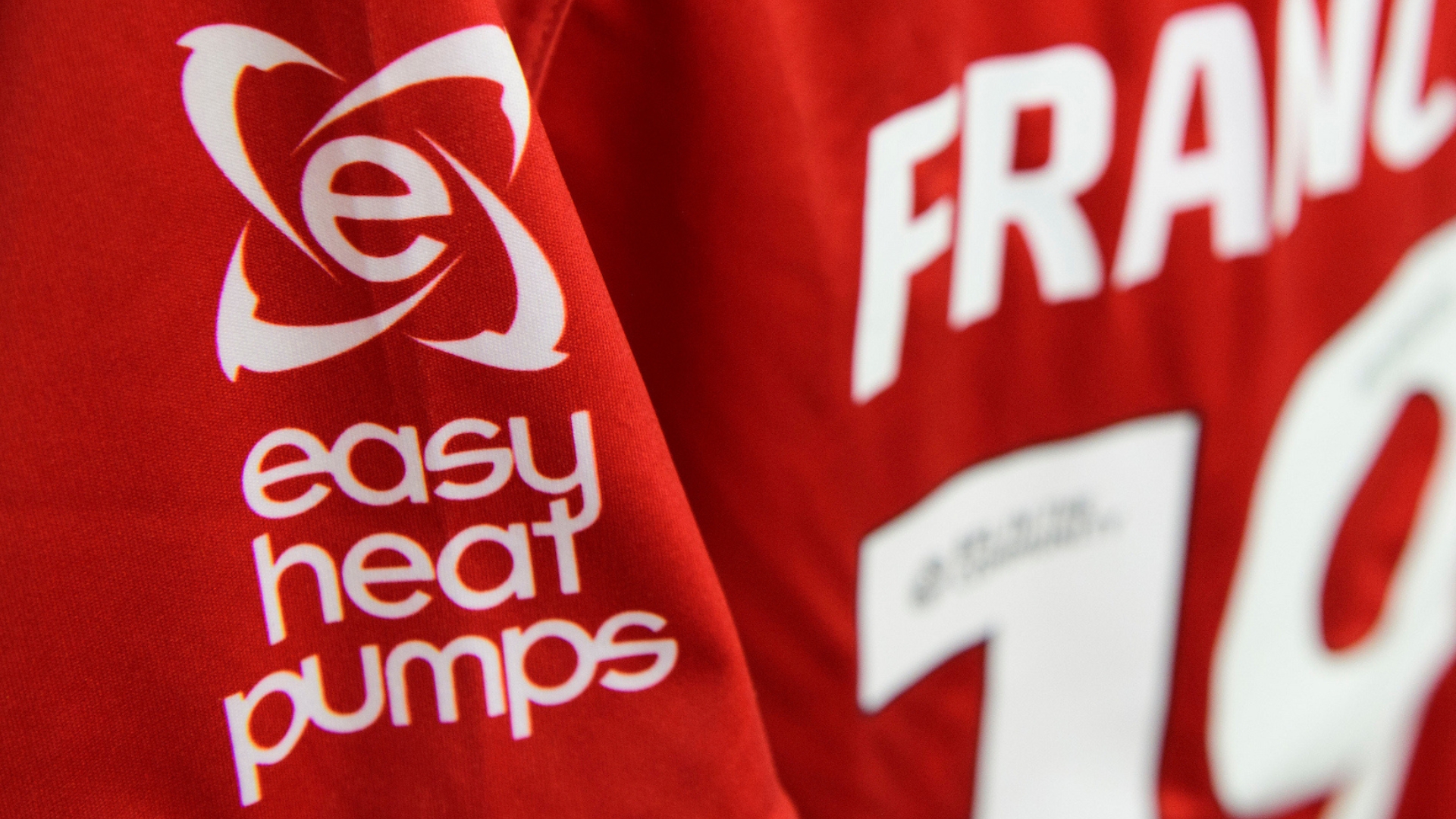 The Easy Heat Pumps logo on the sleeve of the home shirt worn by Frankie Okoronkwo of Lincoln City in the changing room prior to the Carabao Cup second round match between Burton Albion and Lincoln City at Pirelli Stadium, Burton-upon-Trent.