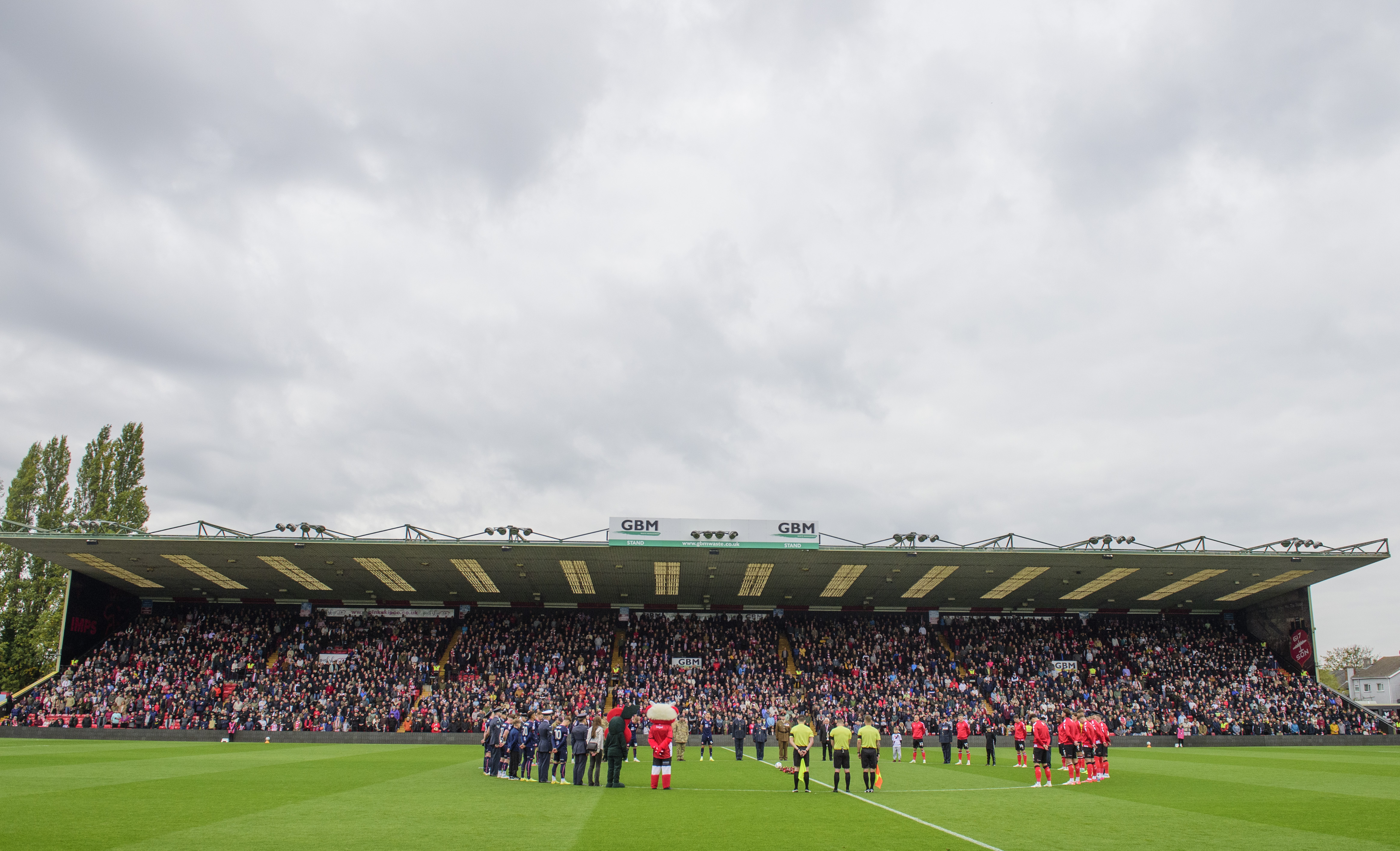 Footballers stand on a pitch