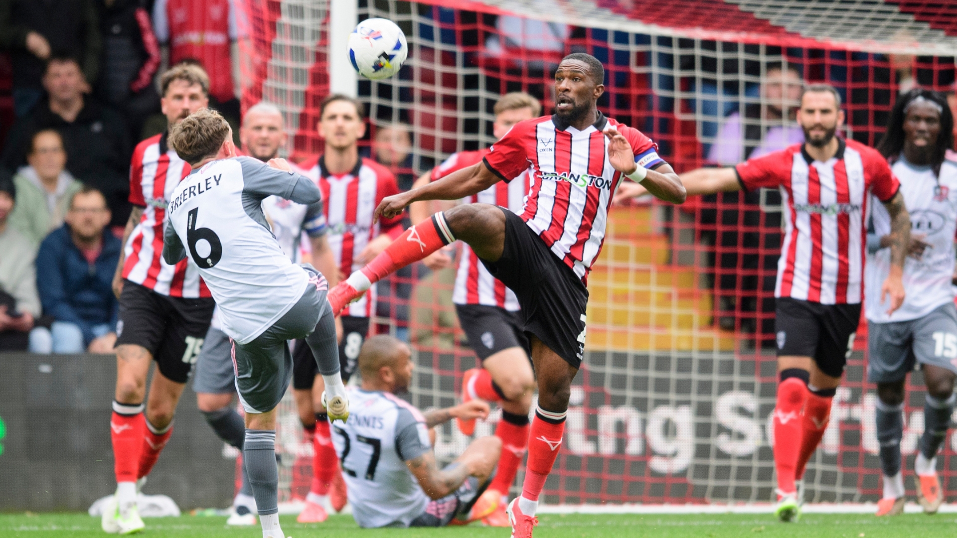 Tendayi Darikwa of Lincoln City clears under pressure from Ethan Brierley of Exeter City during the EFL Sky Bet League One match between Lincoln City and Exeter City at LNER Stadium, Lincoln.