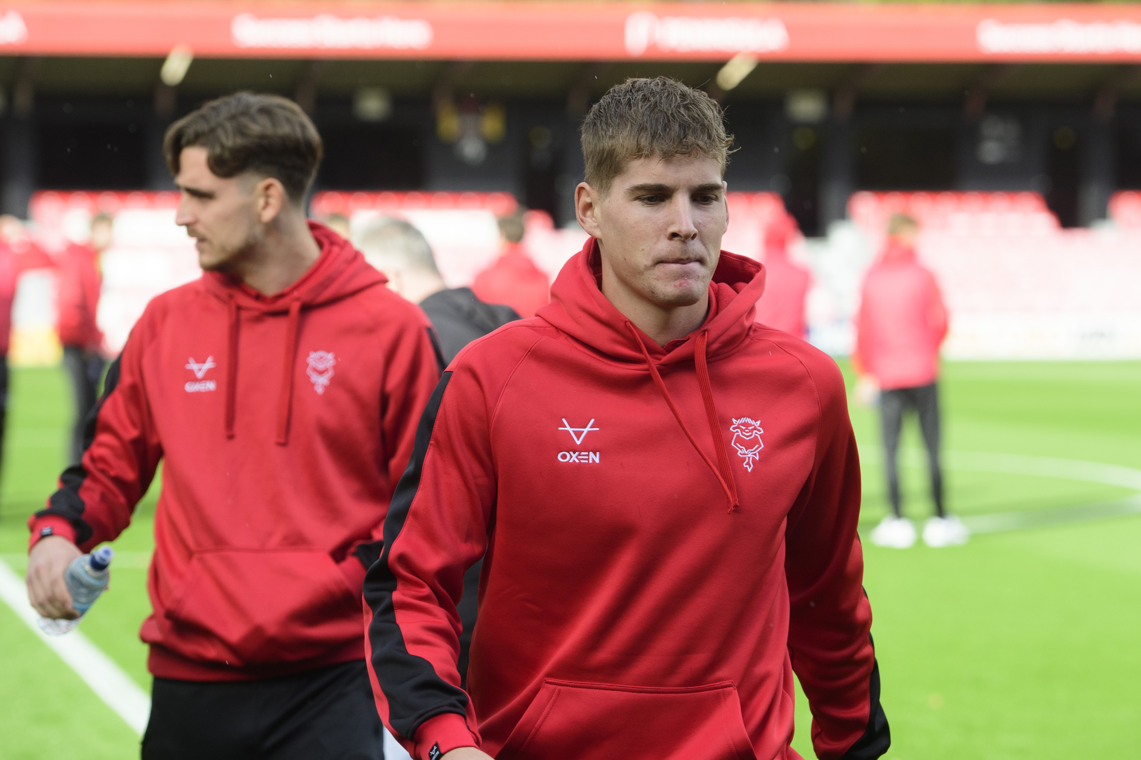 Ivan Varfolomeev, wearing a red hoody, walks off a football pitch towards the camera.