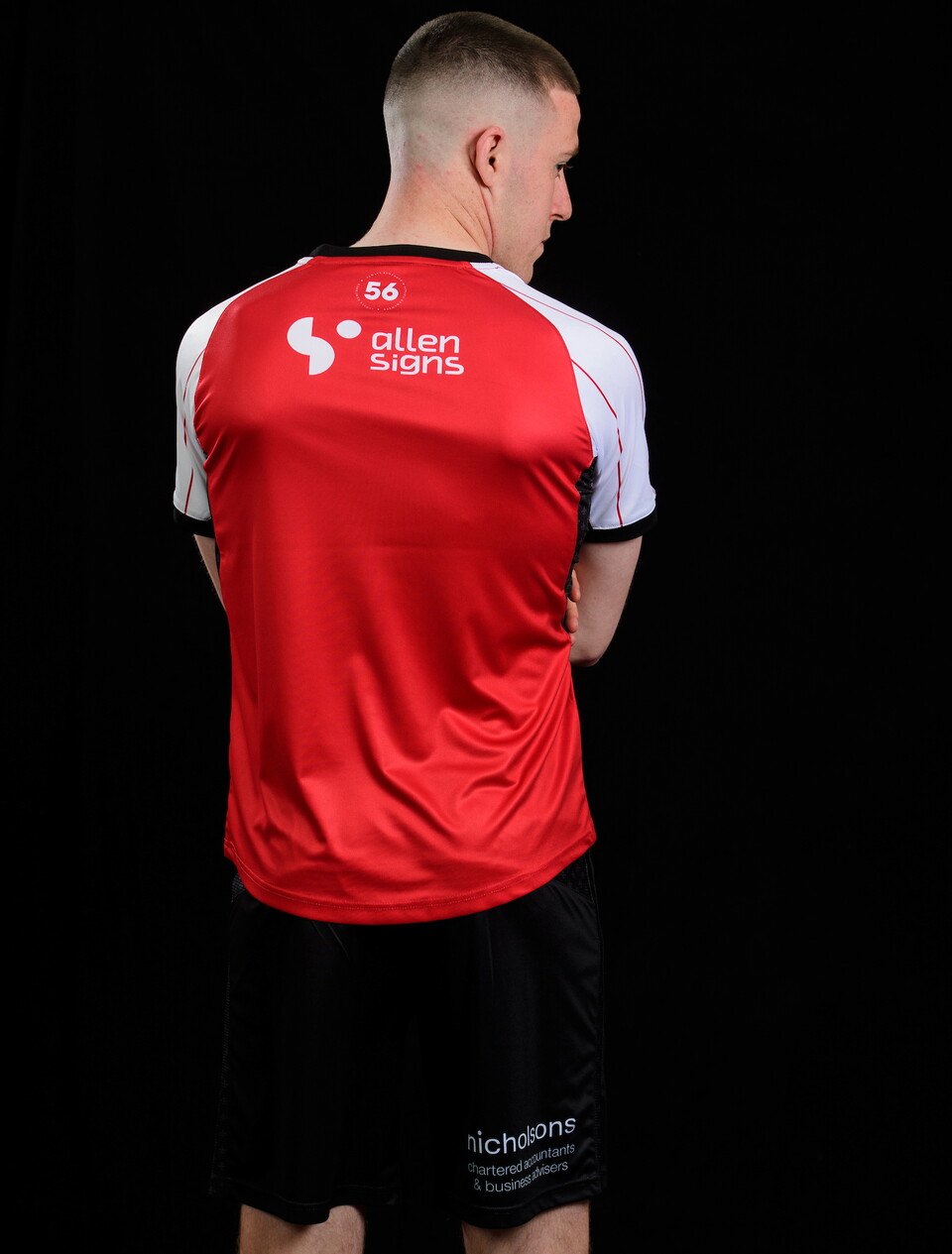 Jack Moylan wears the 24/25 home kit. It is red and logos for Allen Signs and Nicholsons are clearly visible.