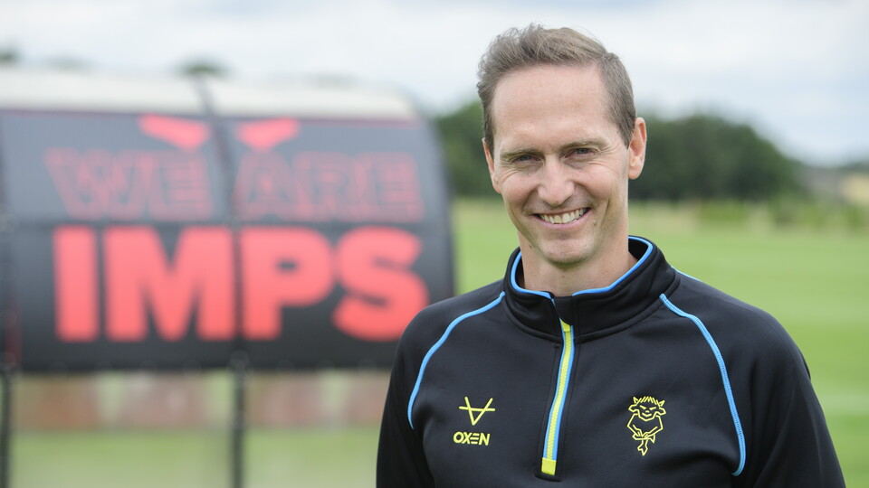 David Bridges poses for the camera in a black training top.