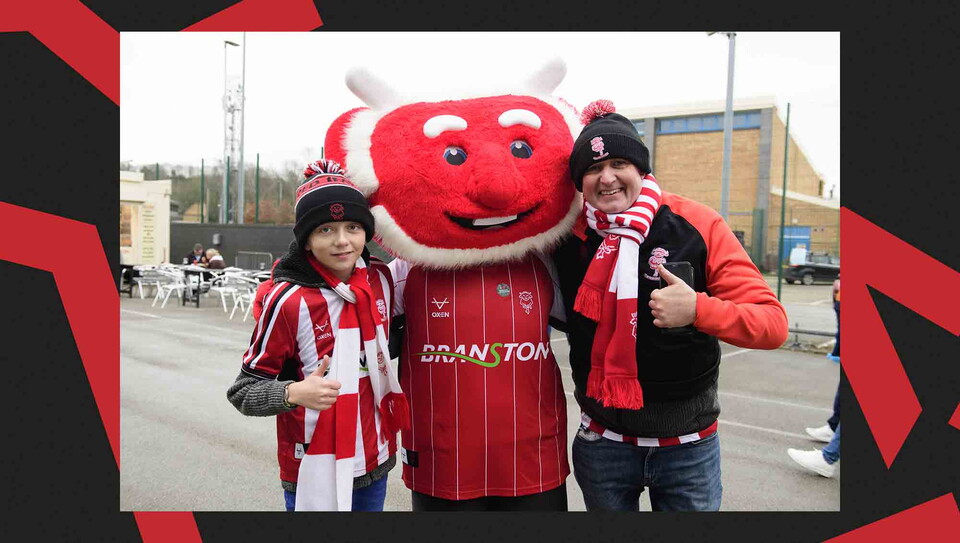 Fans pose for a photo with Poacher the Imp before the game.