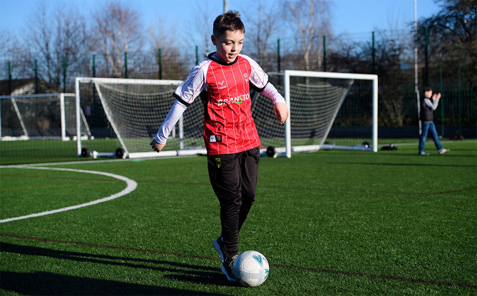 A young Imps fan plays football on the 3G pitch outside the LNER Stadium