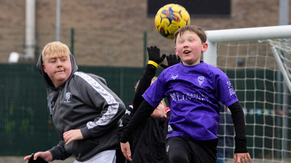Young supporters play football on the 3G pitch outside the LNER Stadium