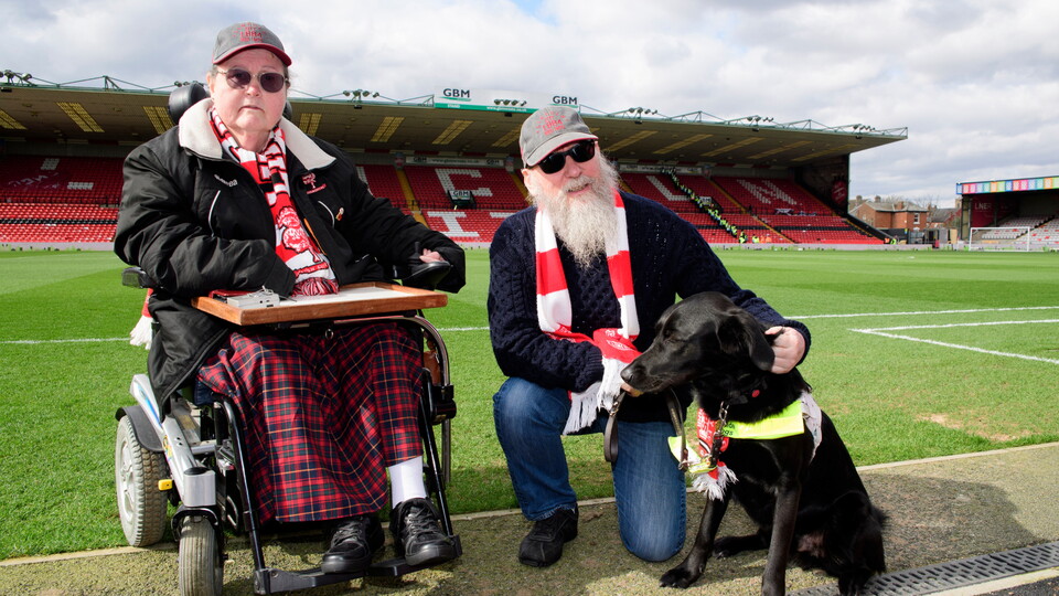 Lincoln City supporters with their guide dog inside LNER Stadium. 