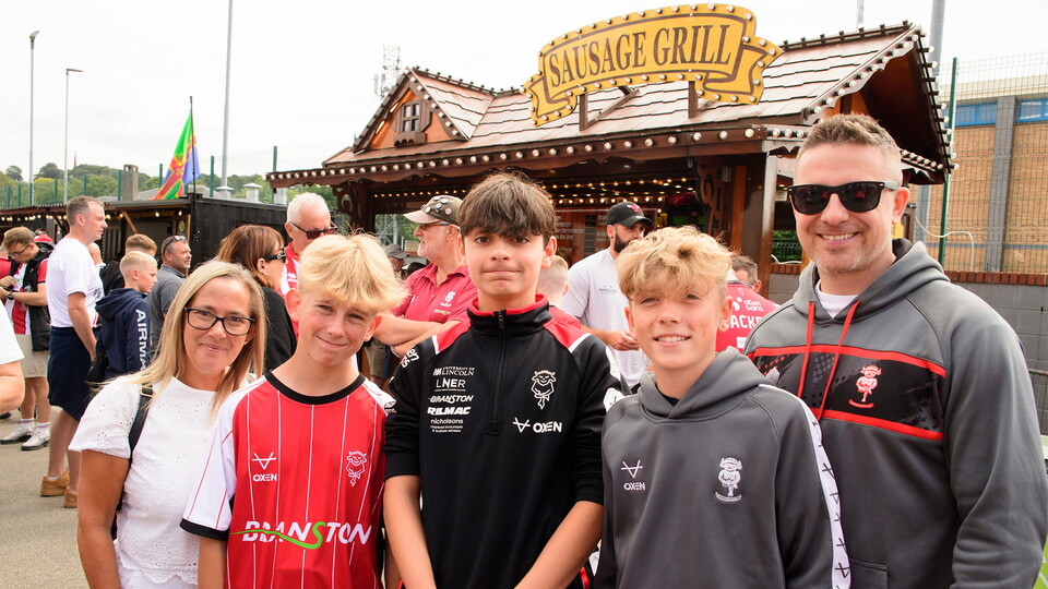 A family of Lincoln City supporters pose for a photograph in the Fan Village outside the LNER Stadium.