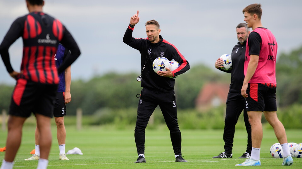 Chris Cohen holds a football as he points during a coaching session