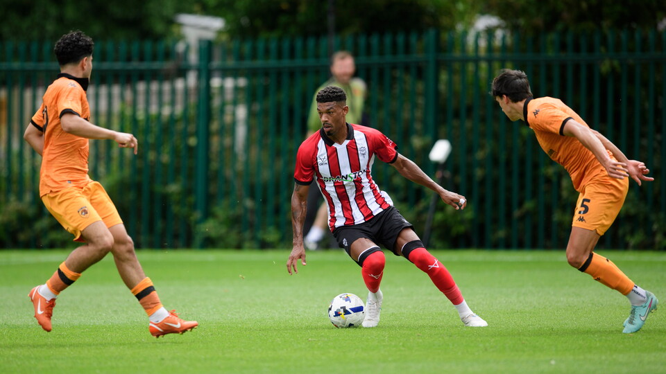 Reeco Hackett runs with the ball. There are two Hull City players closing him down.