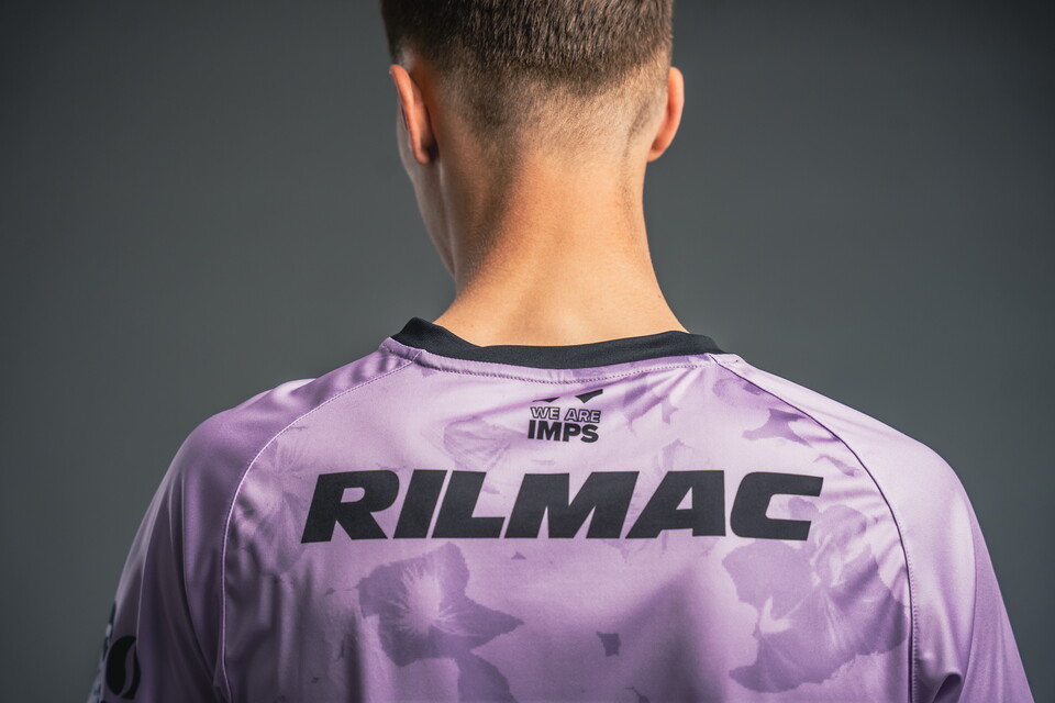 A black Rilmac logo on the back of a violet football shirt