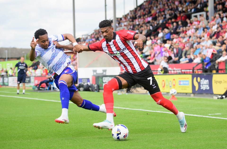 Reeco Hackett of Lincoln City crosses the ball despite the attentions of Kelvin Abrefa of Reading during the EFL Sky Bet League One match between Lincoln City and Reading at LNER Stadium, Lincoln.