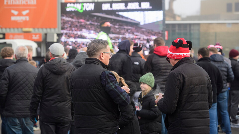 Fans watch football on the big screen in the Fan Village