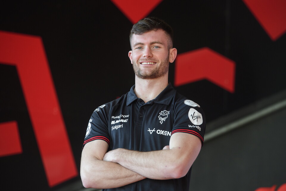 Josh Honohan stands in a black polo top and his arms crossed.