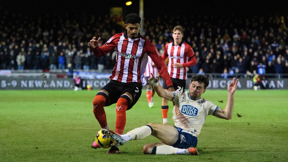 Reeco Hackett of Lincoln City vies for possession with Sean Roughan of Huddersfield Town during the EFL Sky Bet League One match between Lincoln City and Huddersfield Town at LNER Stadium, Lincoln.