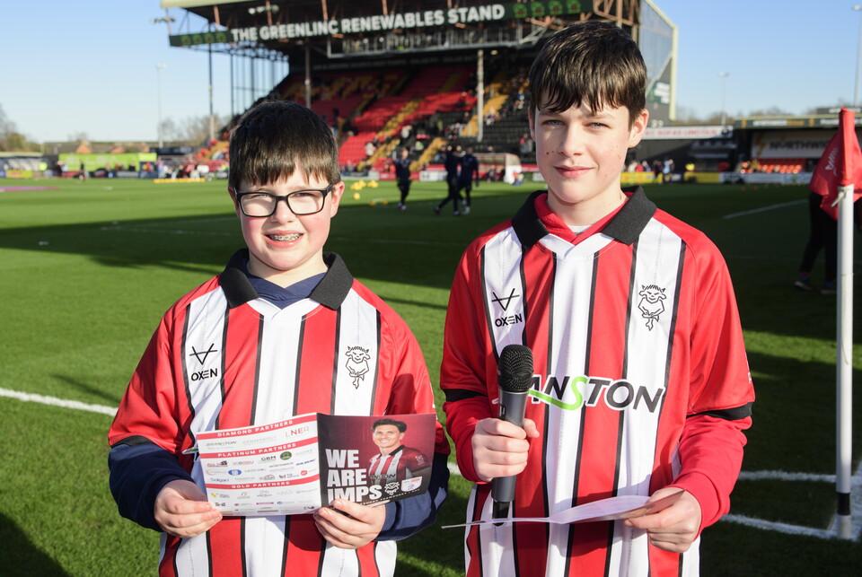 Two boys hold teamsheets and microphones