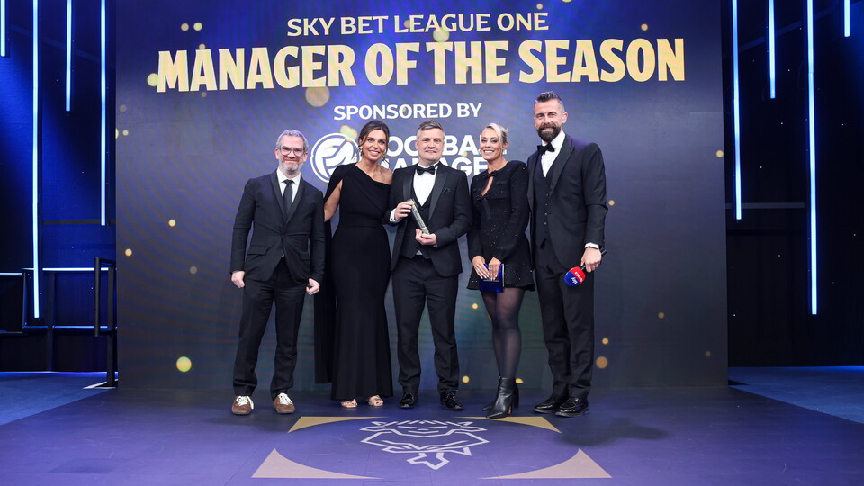 Michael Skubala poses with a trophy surrounded by four other people stood on a stage at the EFL Awards