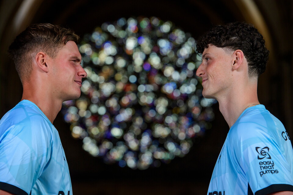 A close up of two people in blue shirts with a stained glass window in the background
