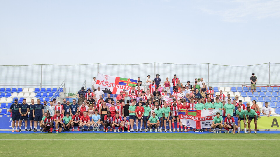 Supporters and players pose at a stand